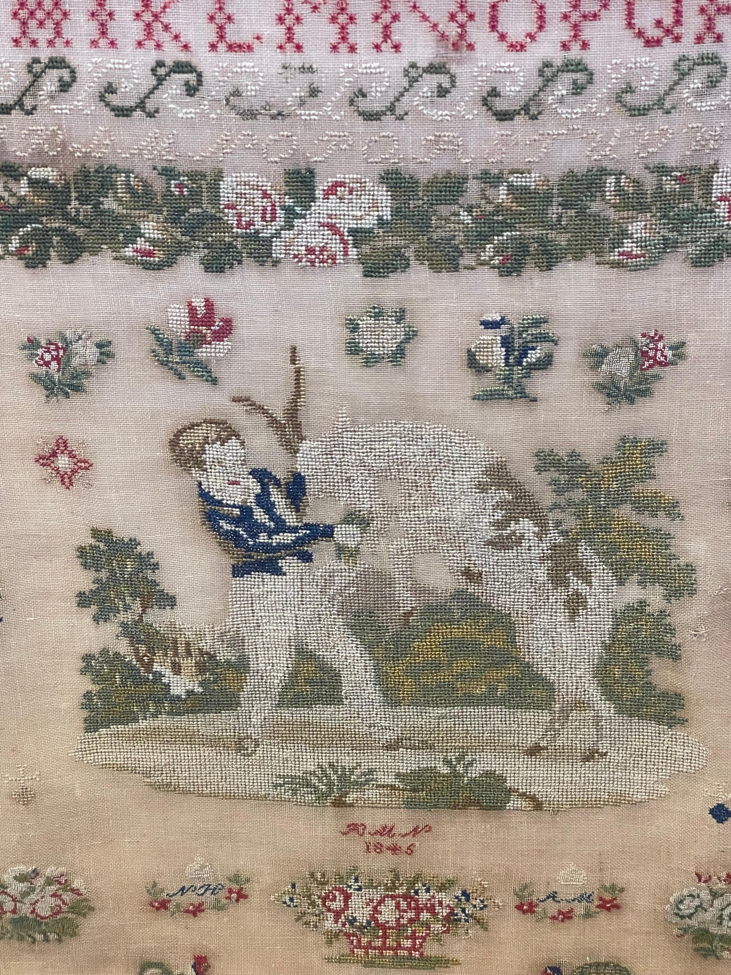 Likely English, this needlework sampler features two alphabet rows; one in block and one in script. The central motif features a boy with a handful of carrots a pony on its hind legs, with lower initials 