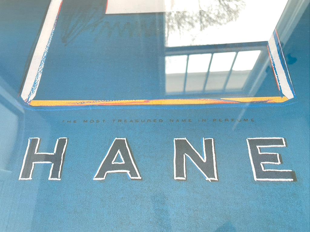 Ce magnifique poster pop art vintage de Chanel est présenté dans un cadre blanc moderne, avec un fond bleu et noir. Ce poster est monté sur lin et représente le luxueux flacon de parfum Chanel n° 5, l'une des quatre variétés de couleurs audacieuses