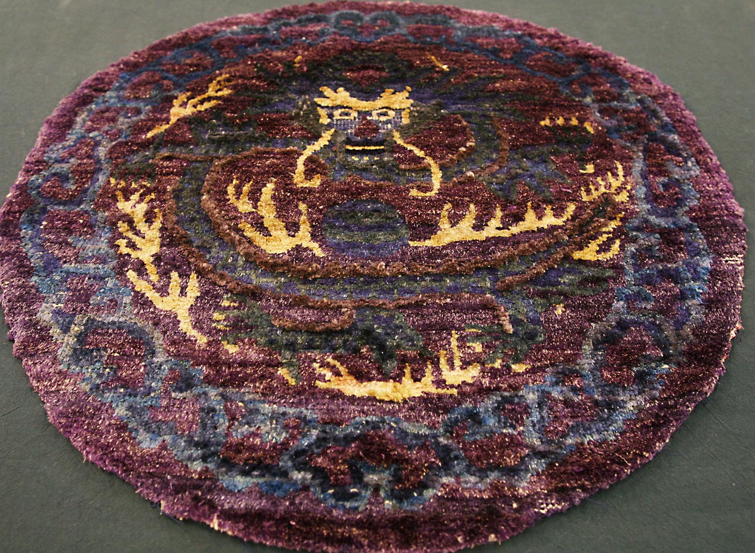 This is an antique silk Peking circular rug woven in China during the 19th century and measures 60 x 60CM in size. This is an extremely special rug with a highly unique purple background color and the classical dragon motif in the center. Its border