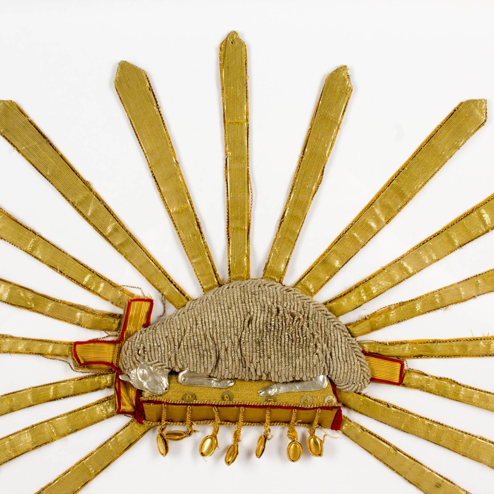 This beautifully made antique (late 1800s) textile fragment features an embroidered image of the Lamb of God, a symbol for Christ, surrounded by light. The embroidery is not flat, but rather three-dimensional. We believe this particular fragment was