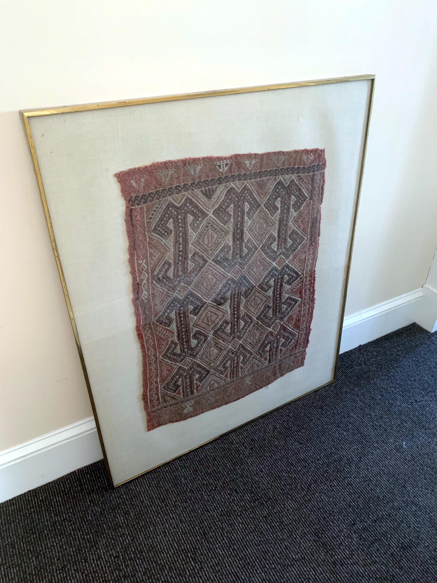 A framed fragment of textile that used to belong to the collection of the Bank of New York. It is identified as a Turkish Cicim Yastik, a cushion cover. Bold geometrical patterns of large quadruple hook called Ram's Horns occupy most the surface,