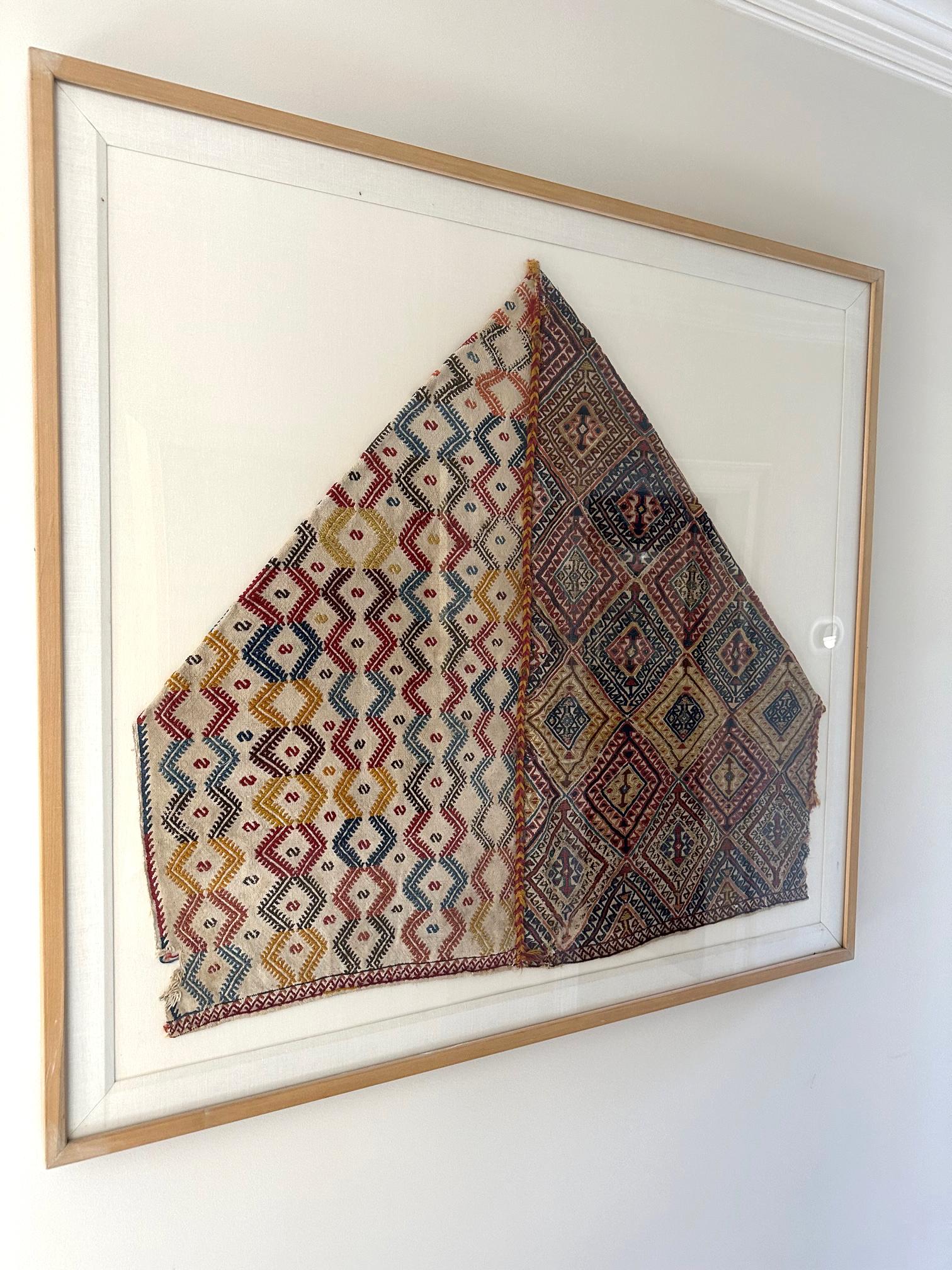 A professionally framed antique hand-woven Turkish textile from Anatolia circa late 19th century. The panel was likely a storage bag face. It features a striking joined panels that showcase respective geometrical motifs. One side shows S hook