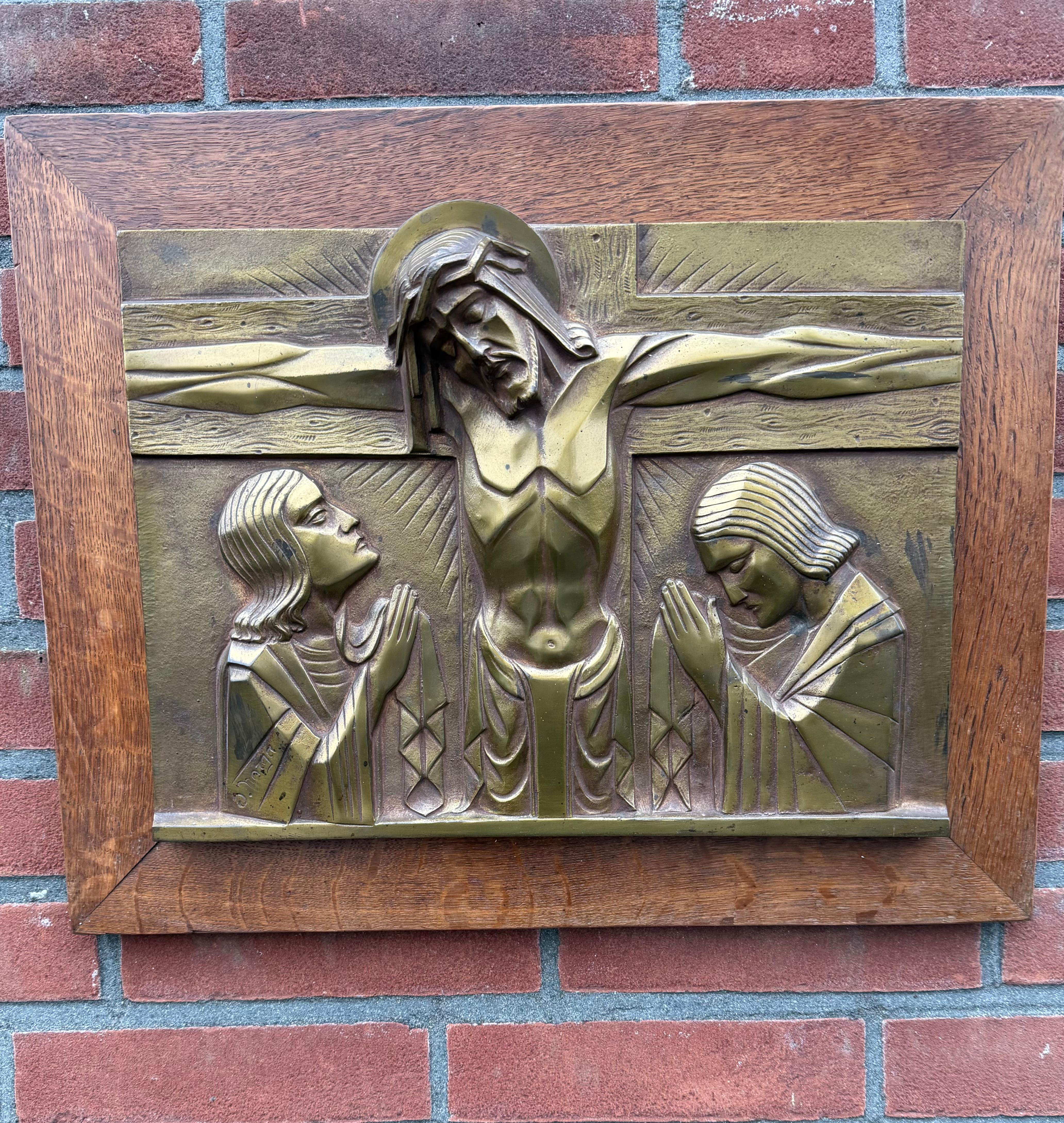 Œuvre d'art religieux parfaitement stylisée de S. Norga.

Cette plaque de bronze de taille pratique et très bien conservée, placée dans un élégant cadre en bois de chêne, représente le Christ sur la croix avec Marie et Saint John en deuil de part et