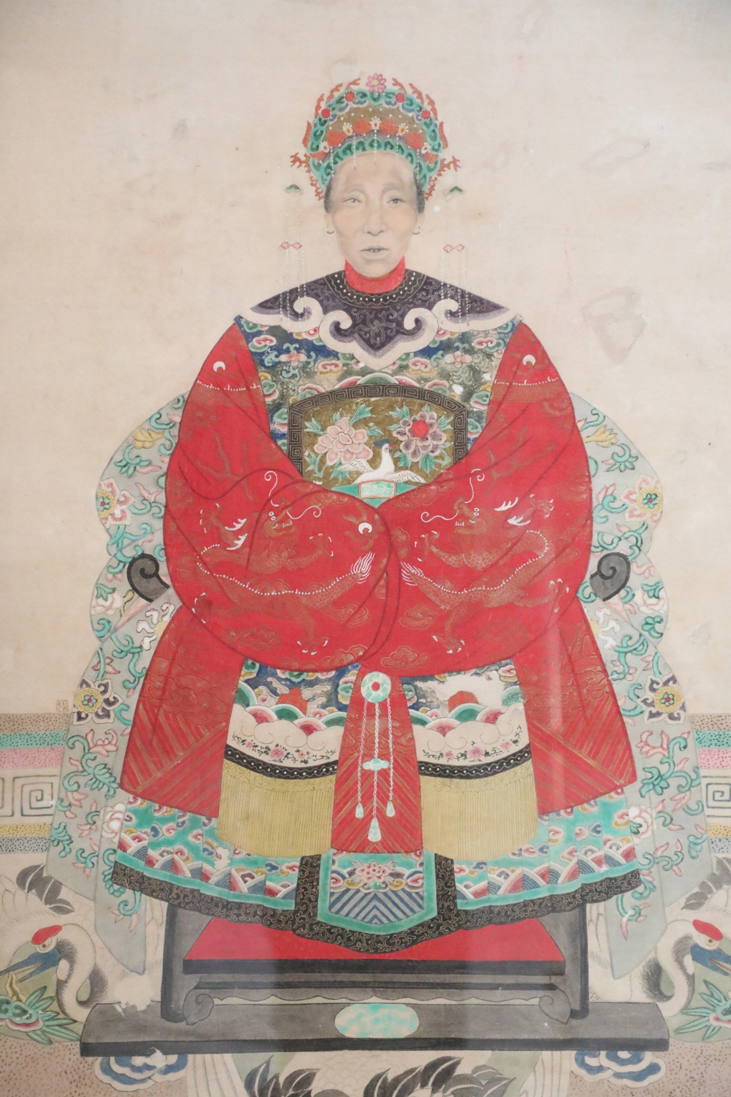 Special listing for mated pair Vintage (20th Century) Chinese ancestor portrait capturing the honoree seated and wearing an elaborate hat and red dress, on a beige background, and a floor patterned with several cranes, set in a rectangular wood