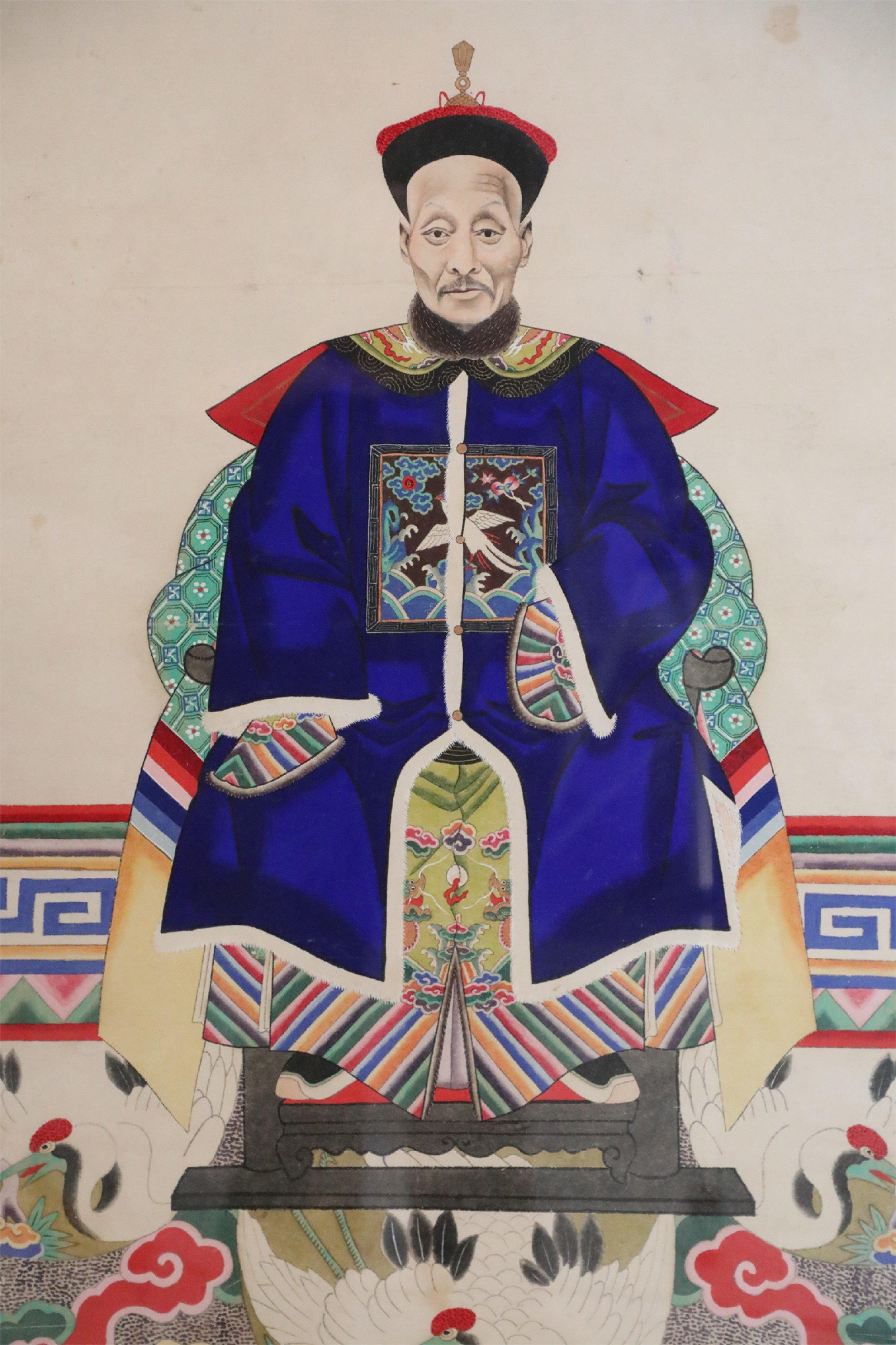 Vintage (20th Century) Chinese ancestor portrait capturing the honoree seated and wearing a royal blue dress, on a beige background, and a floor patterned with several cranes, set in a rectangular wood frame.
   