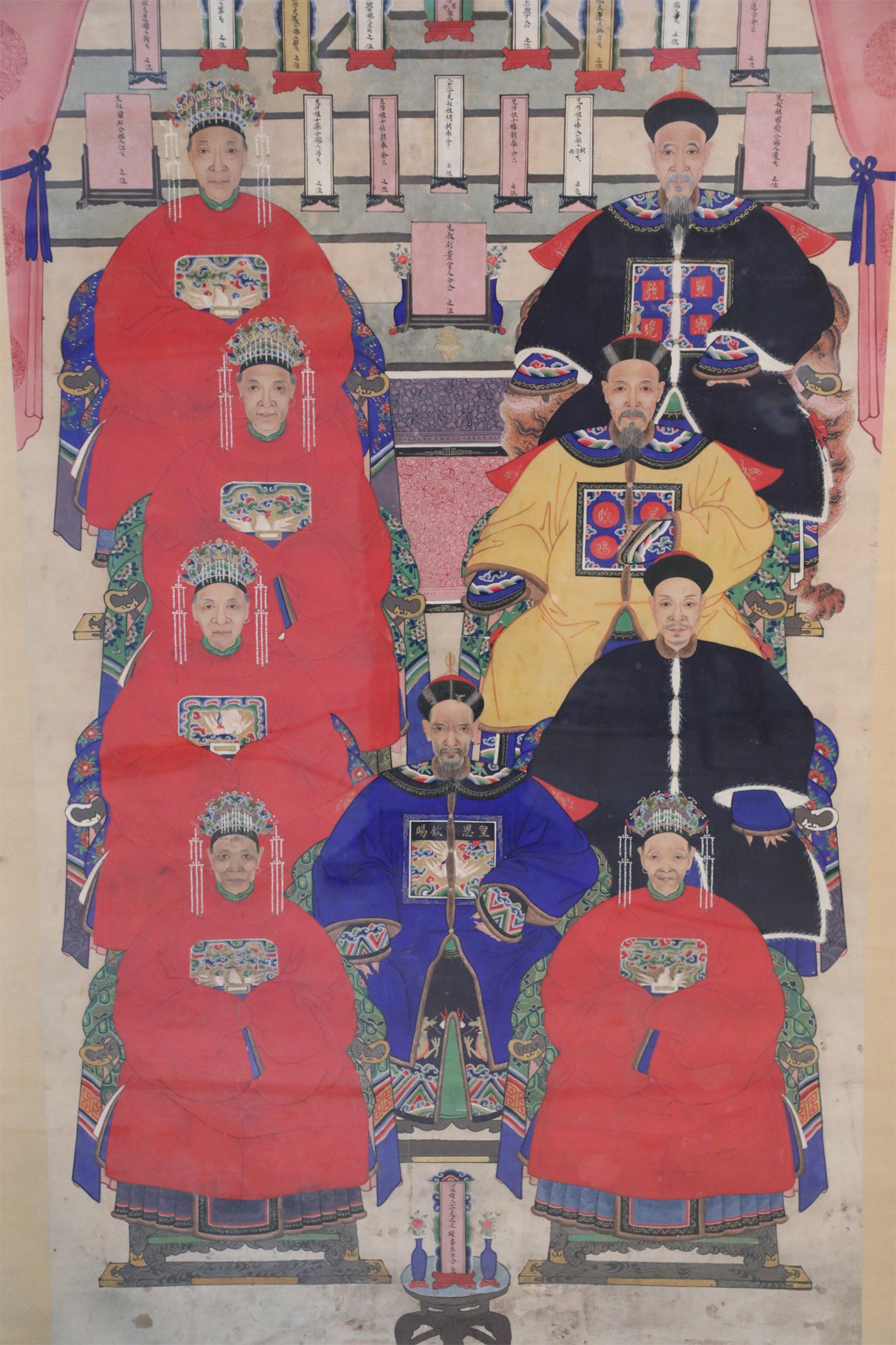 Vintage (20th Century) Chinese pen and ink family ancestor portrait capturing nine honorees seated in front of scrolls bearing text framed by curtains, and wearing elaborate robes, with beige patterned fabric matting, set in a rectangular, rounded