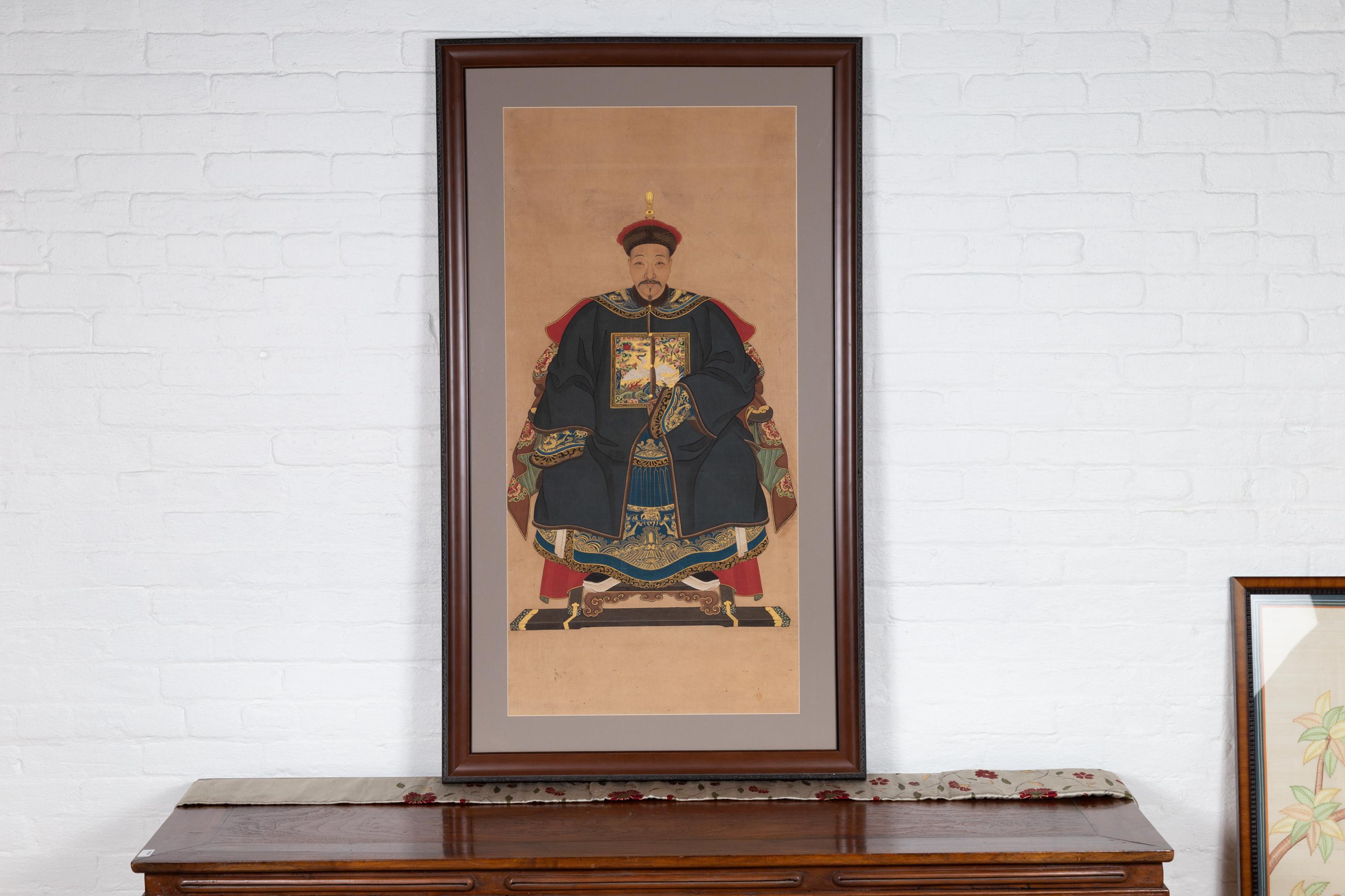 An antique Chinese Qing dynasty period framed ancestral portrait from the early 20th century depicting a patriarch. Born in China during the early years of the 20th century, this exquisite portrait features a high ranking official depicted seated in