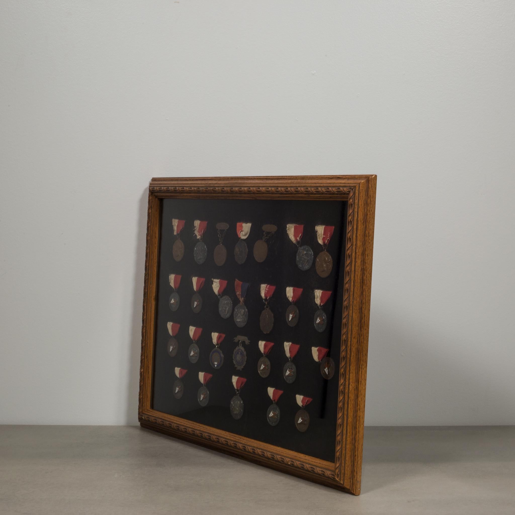 This is a framed display of 26 senior school and university medallions in bronze and silver dating as early as 1904. 23 have their original fabric ribbons and three have an engraved senior pin. They are mounted on black velvet fabric with have been