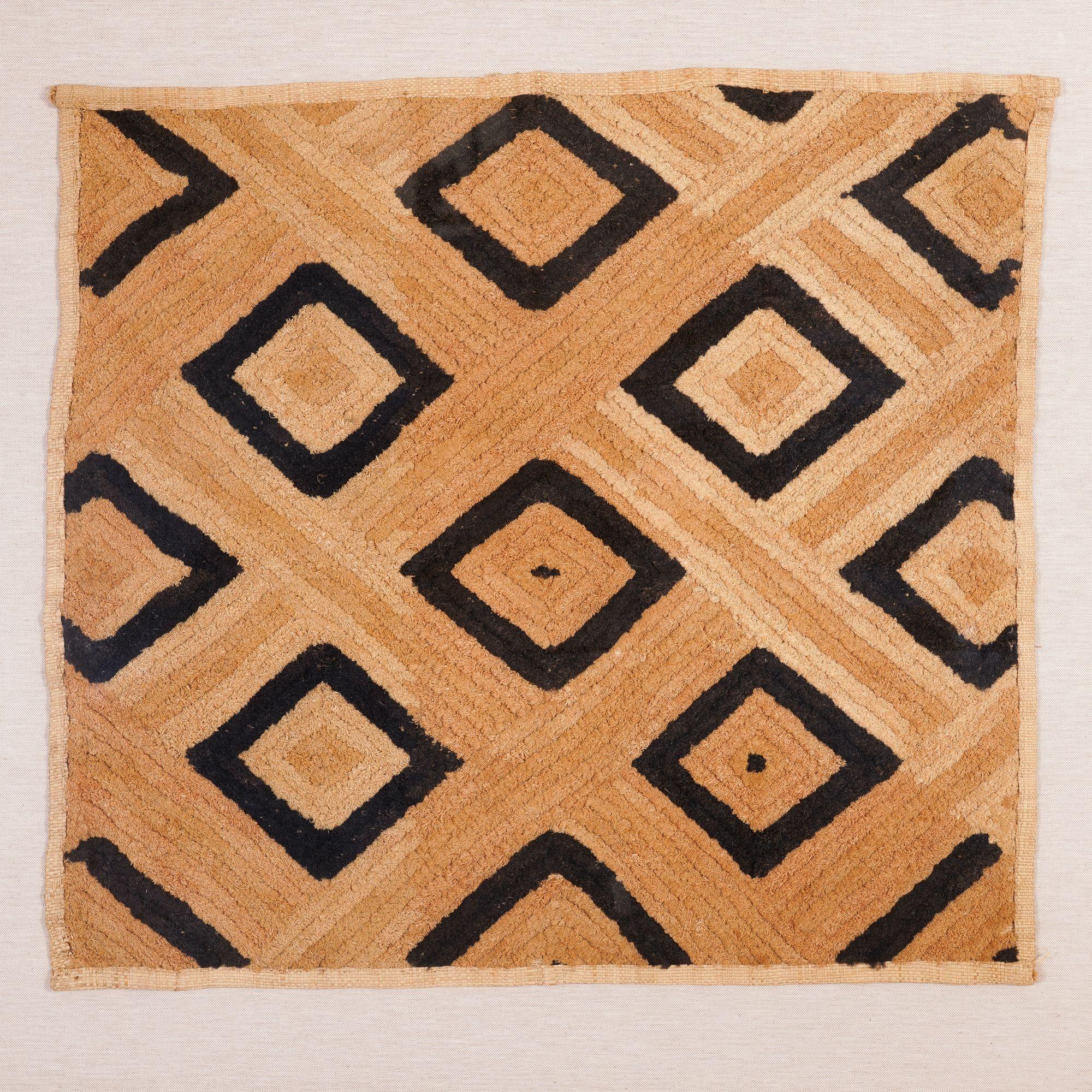 Westafrikanische Kuba-Stoffmatte aus Palmfasern, gewebt auf einem Grund aus Raffiabast in einem geometrischen Muster aus gefärbten und natürlichen Raffiabastfasern. Archivpassepartout auf einer Stoffleinwand und gerahmt in einer ebonisierten