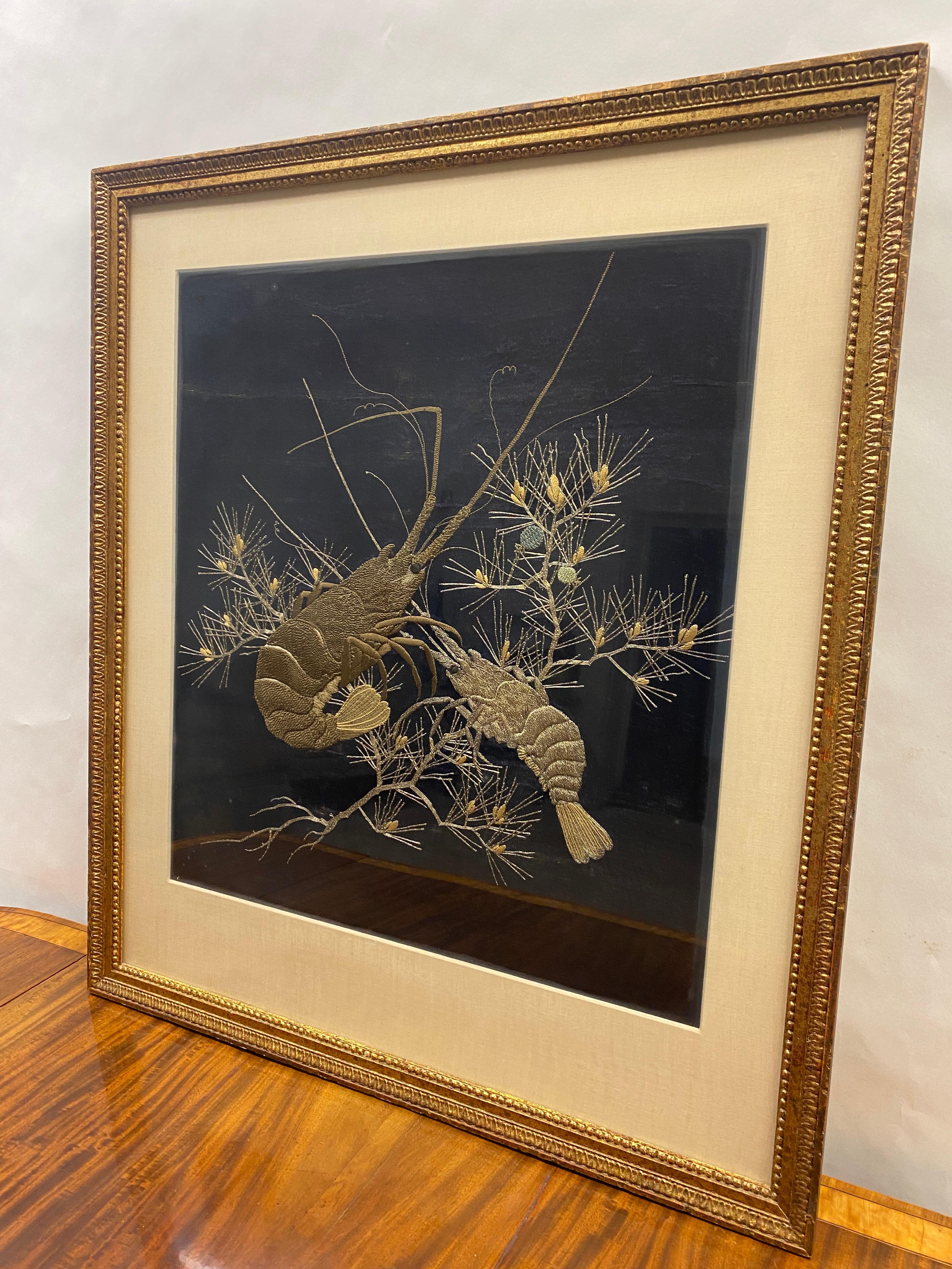 Japanese gold couched thread embroidered scene of two shellfish on a black silk kimono remnant. Mounted inside a gilt frame. 
 Circa 1890-1900.