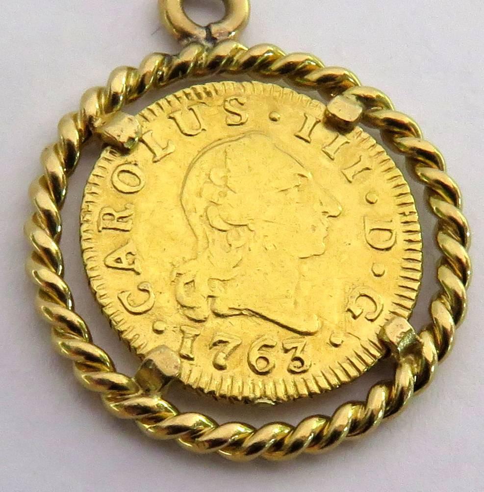 This pendant/charm is mounted in 18k. On the front of the coin is Carolus III D G and dated 1763. On the back is written Hispaniarum Rex, and on the bottom is J M P. with a crest in the center. This coin was made into a charm pendant circa