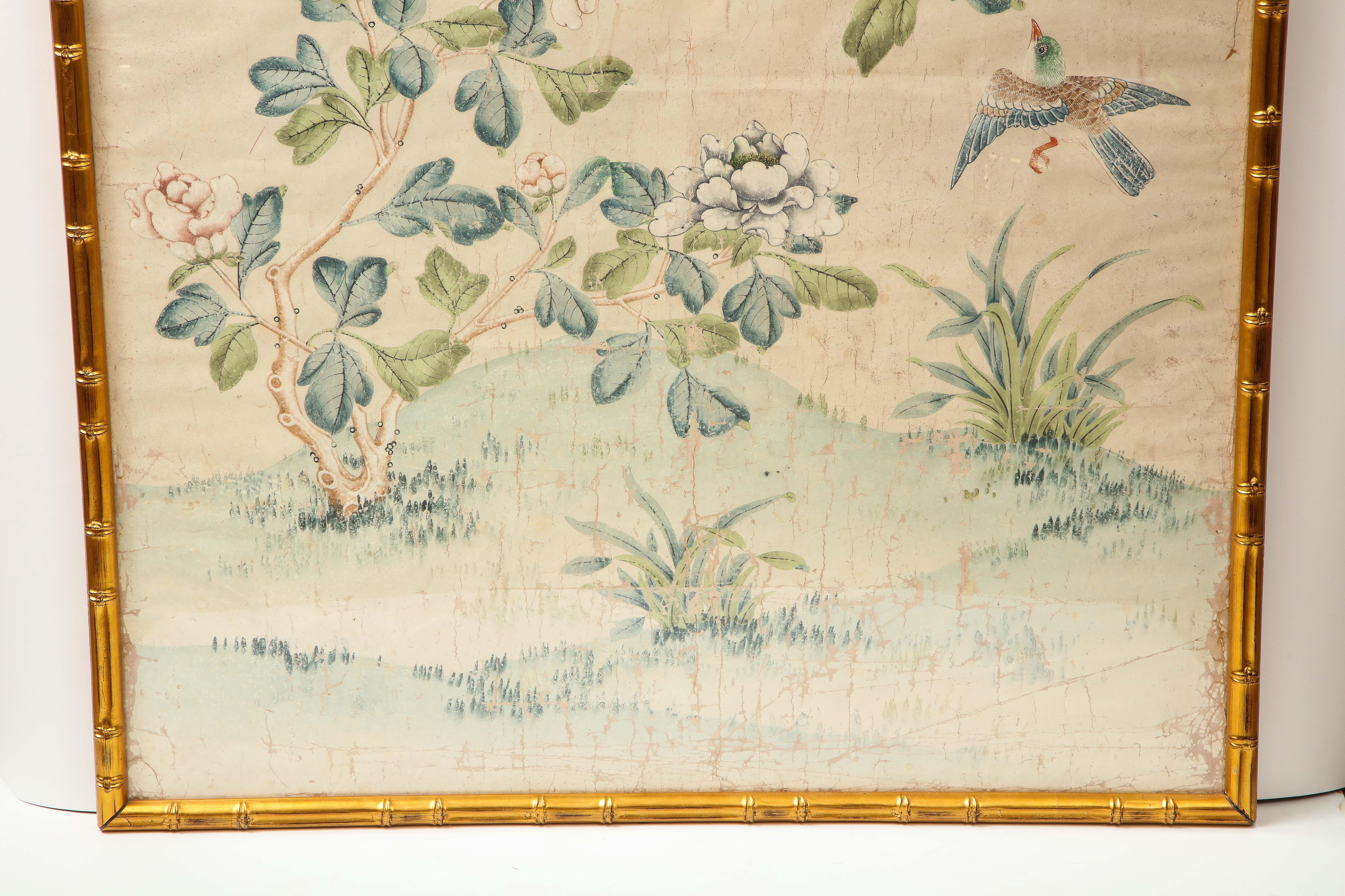 A stunning hand painted wallpaper panel by Gracie in a giltwood faux bamboo frame. The lovely scene is composed of branches, flowers, birds and butterflies in soft, muted tones. This piece could inspire the colors used in a room and is a great way