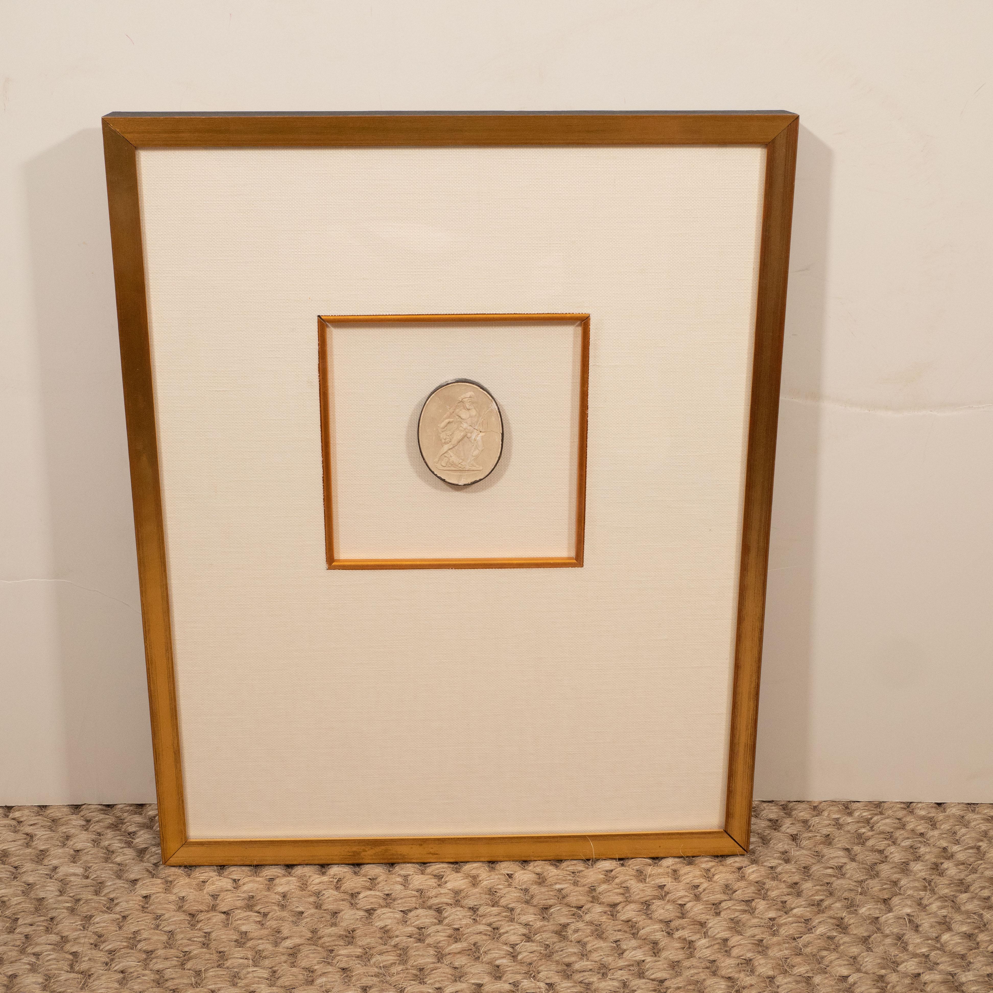A plaster intaglio matted in linen and framed in gold frames with a lovely inner gold fillet. Neutral in color, this piece adds a quiet elegance to a room.