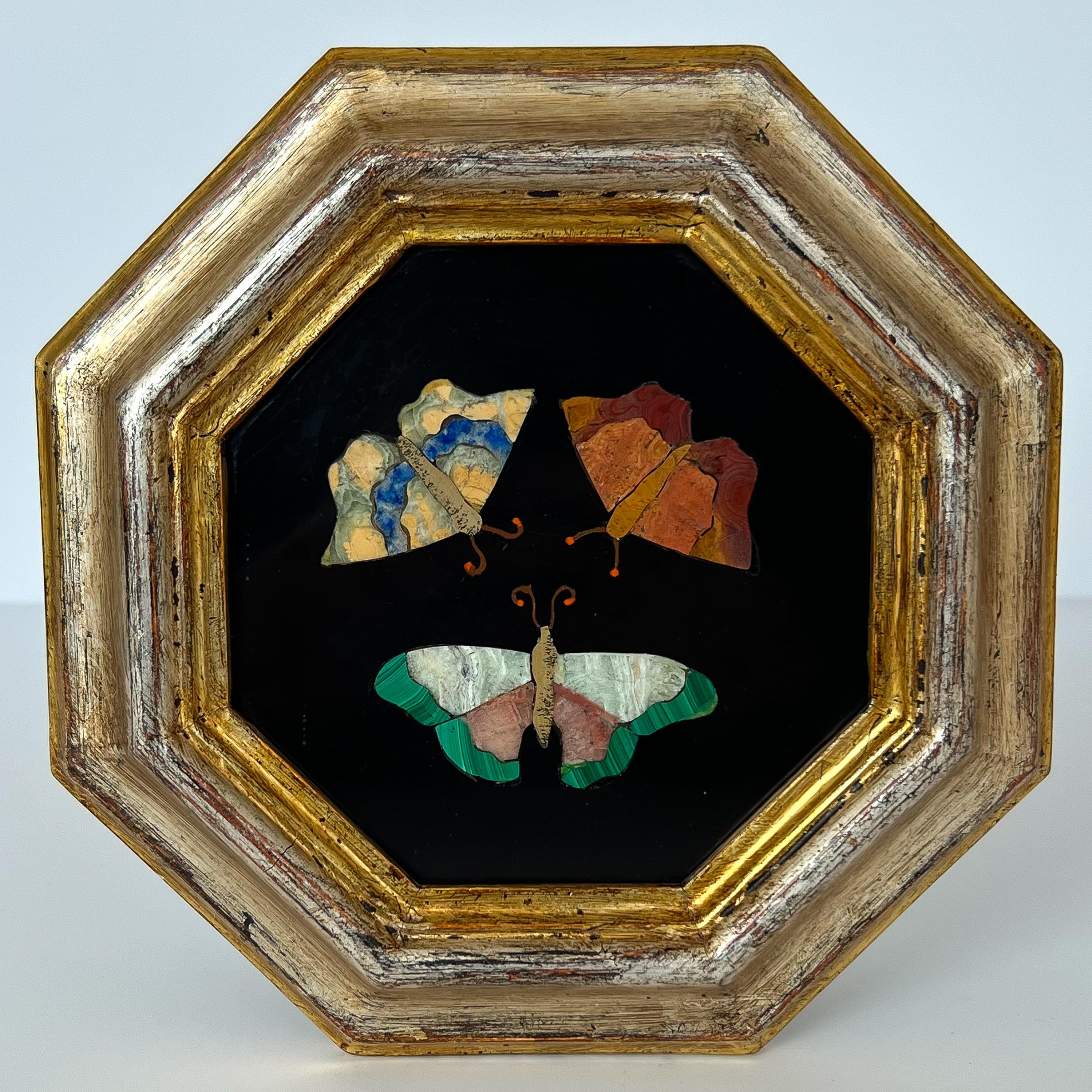 Spring has finally arrived! A framed late 19th century Italian Pietra Dura of three butterflies. Polished black slate inlaid with three butterflies comprised of malachite, marble, lapis and other semi-precious stones. Octagon shaped frame gilt in