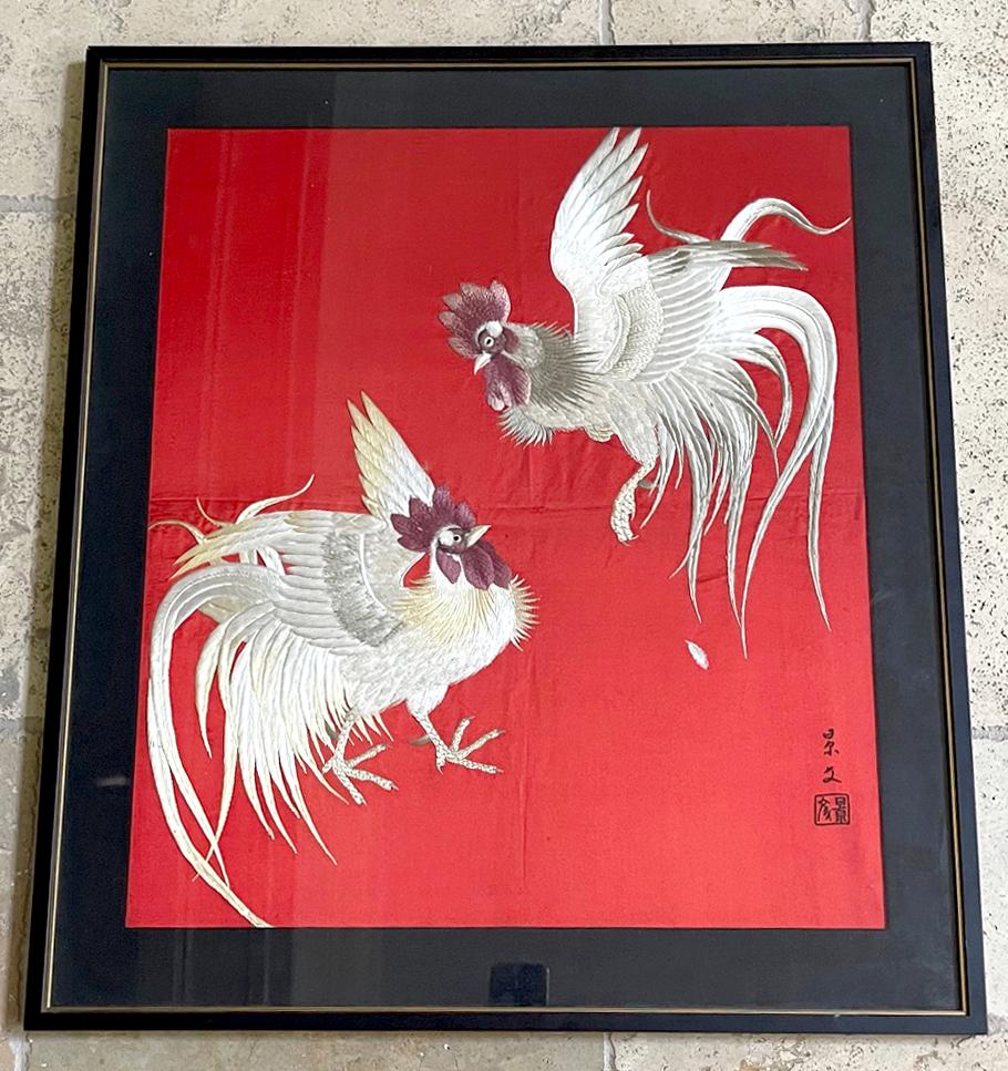 Panneau de soie japonaise encadré et maté, orné de broderies élaborées, datant de la fin de la période Meiji à la période Taisho (1910-30). Sur un fond lumineux, deux coqs ou coquelets au plumage complet apparaissent en train de se battre. Les