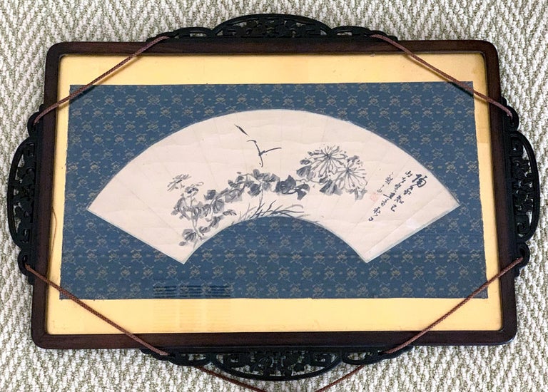An ink painting on the fan surface by Japanese Zen artist Hidaka Tetsuo (1791-1871), now framed in a traditional Japanese carved wood frame with silk fabric mat and decorative hanging tassels. The painting depicts a floral group consisting of autumn