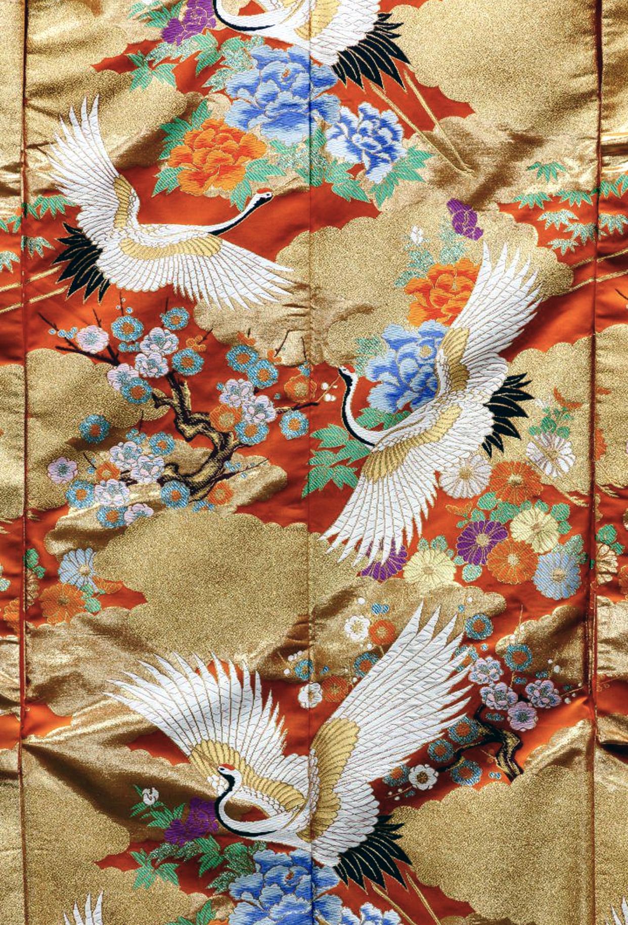 A large Japanese Wedding Kimono nicely framed with linen backing. The auspicious ceremonial attire was elaborated embroidered with flying cranes and blooming flowers such as peonies in various colors. The deep orange brocade background was further