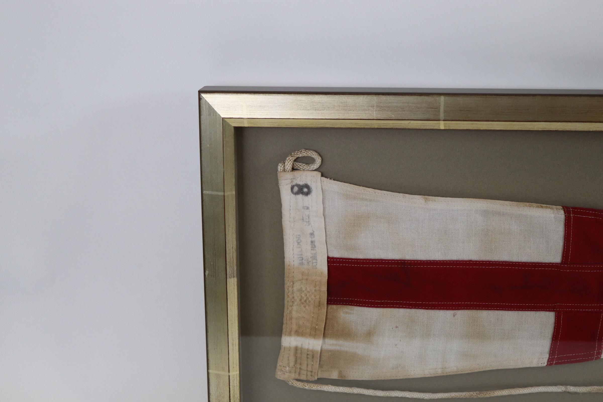 Shadow box framed ships signal flag with attached rope and wood toggle. White field with Red Cross. Weight is 5 pounds.