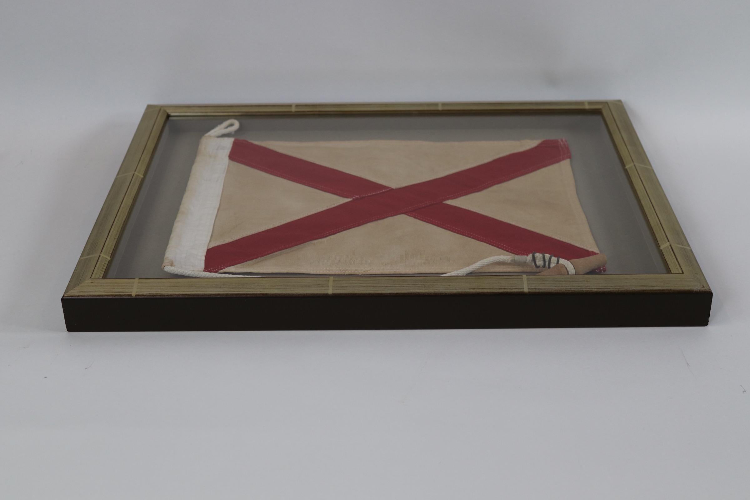 Shadow box framed ships signal flag with attached rope and wood toggle. Red diamond on a white field. Letter V. Weight is 5 pounds.