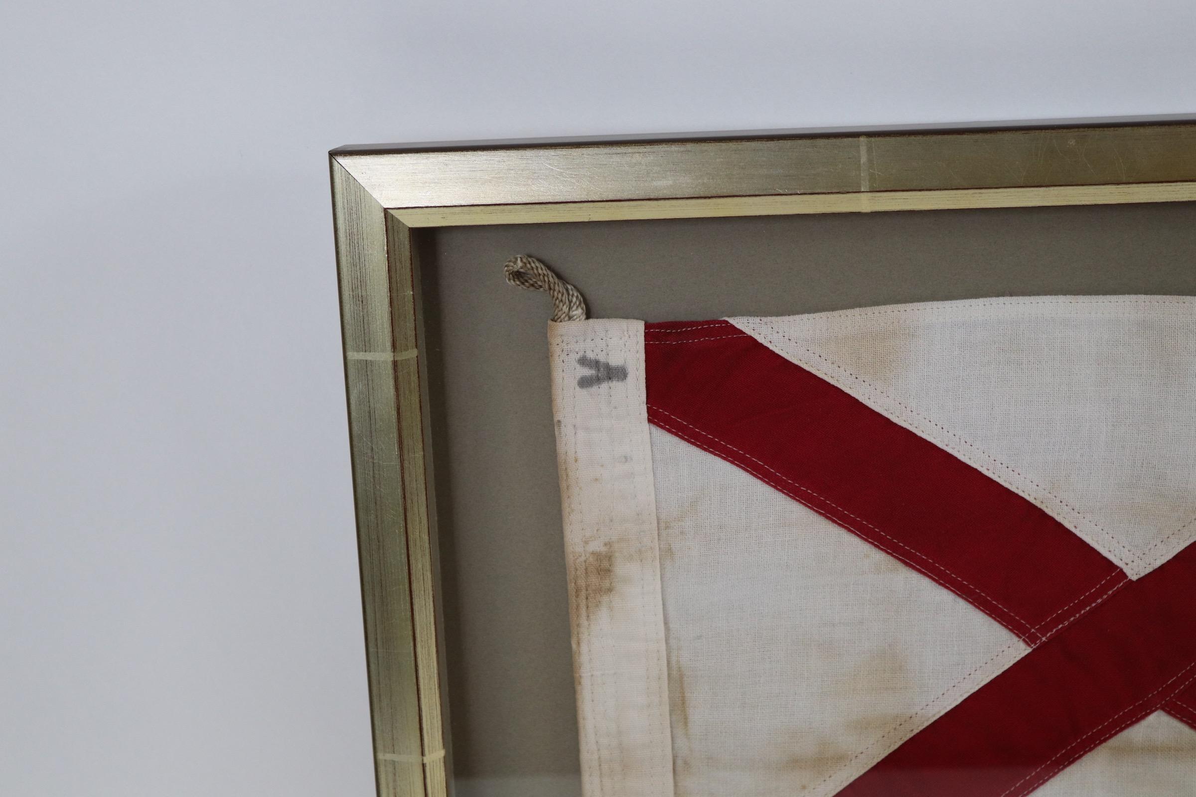 Framed marine pennant representing the letter V set into a shadow box frame with rope and wood toggle. Weight is 5 pounds.