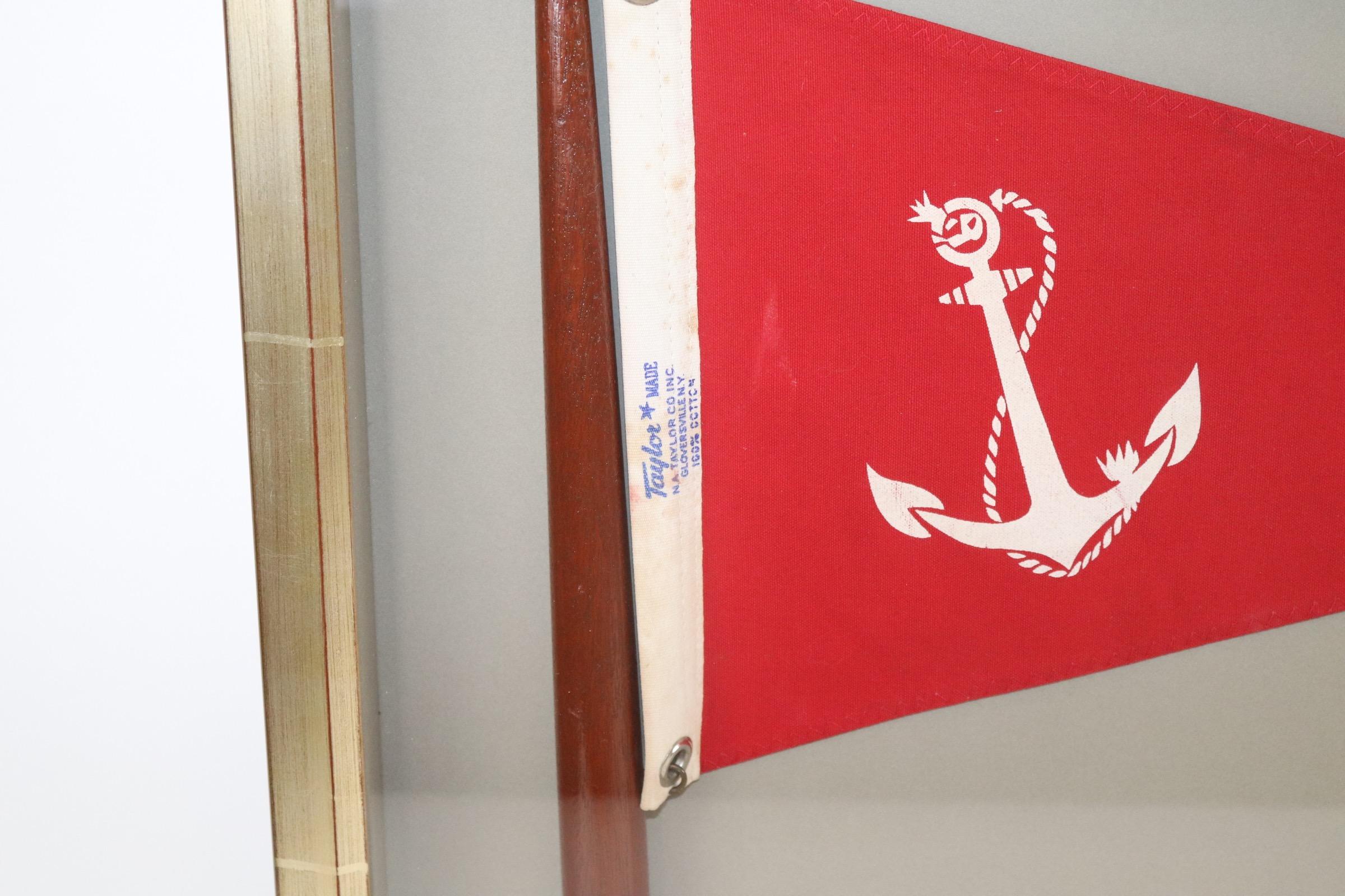 Framed nautical pennant on mast with a red field and white fouled anchor by Taylor. Fitted to a custom shadow box. Weight is 9 pounds.