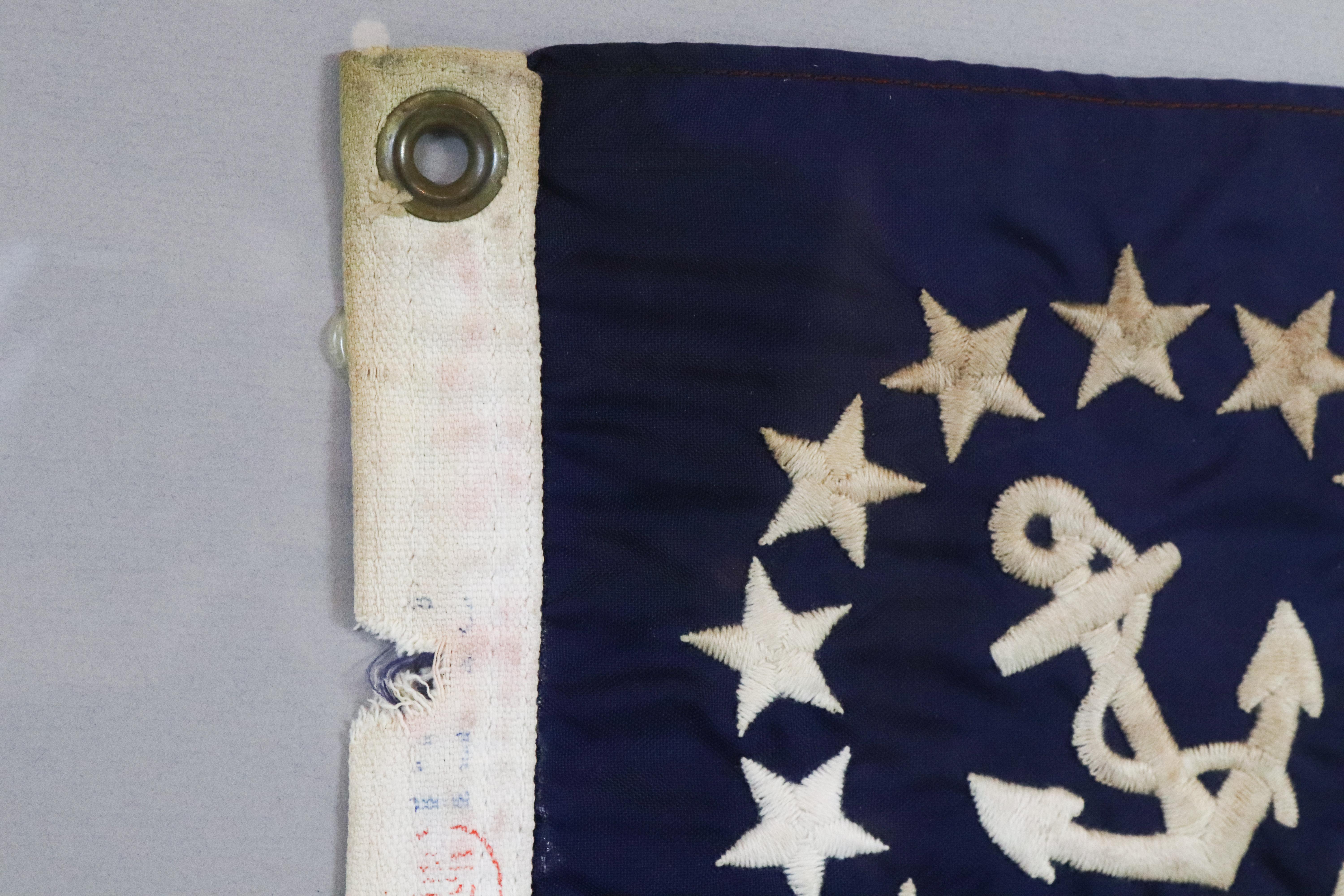 Nicely framed American yacht ensign with embroidered fouled anchor and thirteen stars. Gray matting. Measures: 22