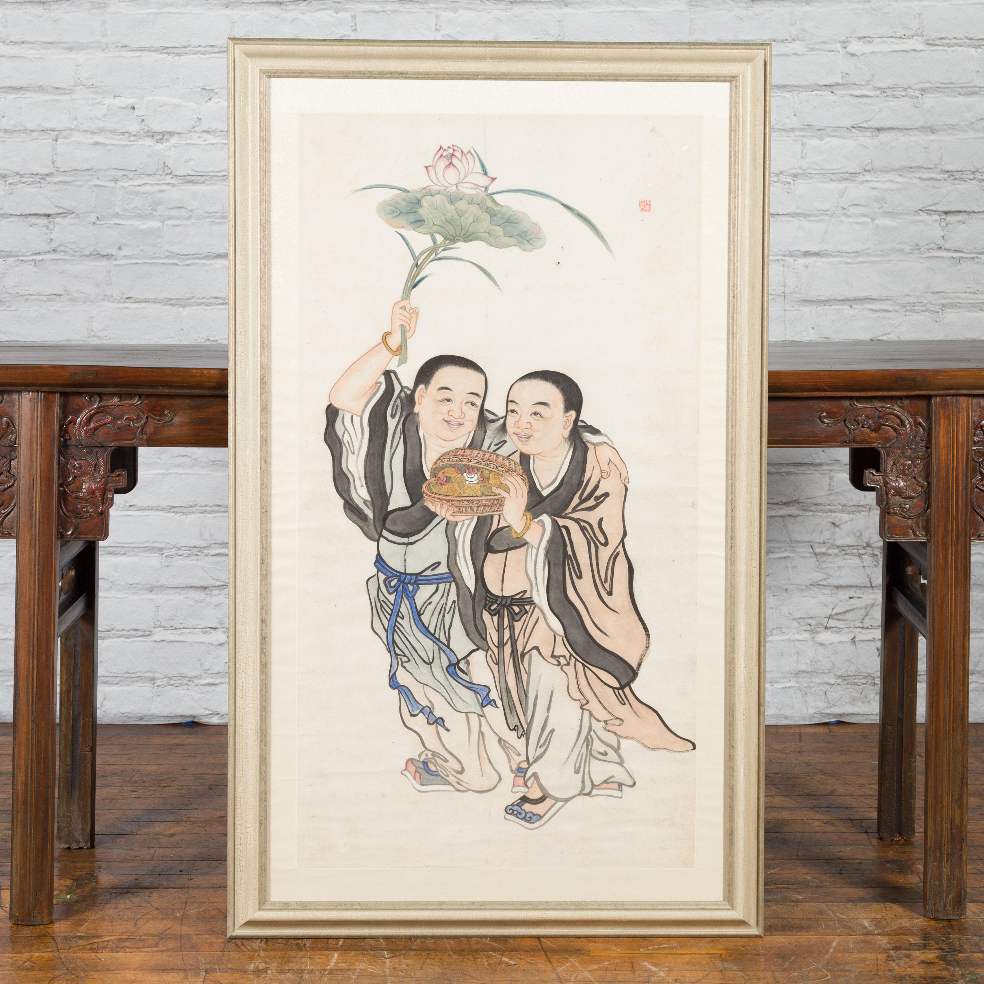 A Japanese framed painting from the 19th century depicting two walking Buddhist monks holding a lotus flower and a wicker box, in custom frame. Created in Japan during the 19th century, this vertical linen canvas painting depicts two Buddhist monks