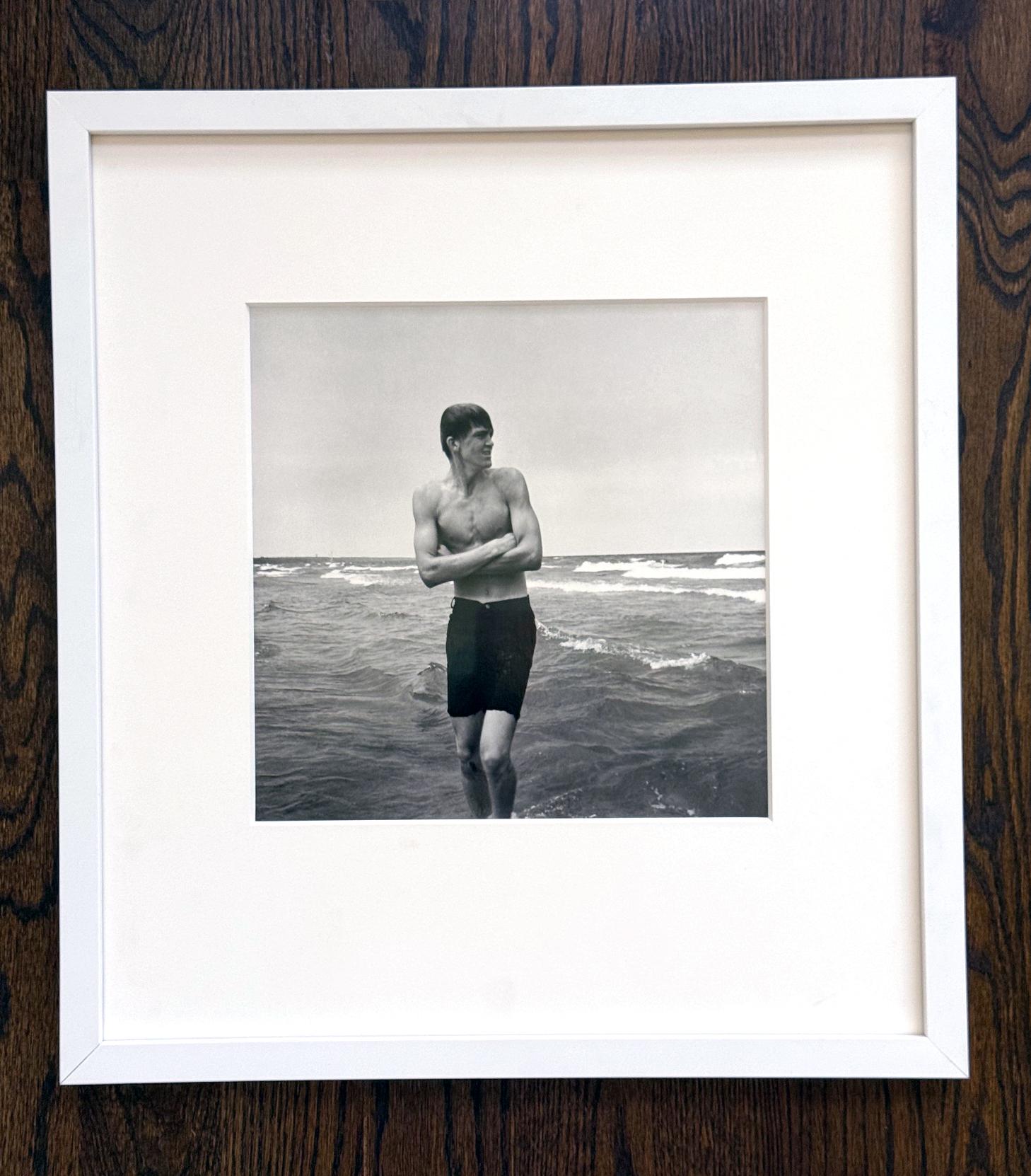 Photographie de rue en noir et blanc encadrée de Vivian Maier (américaine, 1926-2009), Whiting, IL (Young Man at Beach). L'œuvre a été créée à la fin des années 1960. L'épreuve à la gélatine argentique a été imprimée tardivement dans une édition de