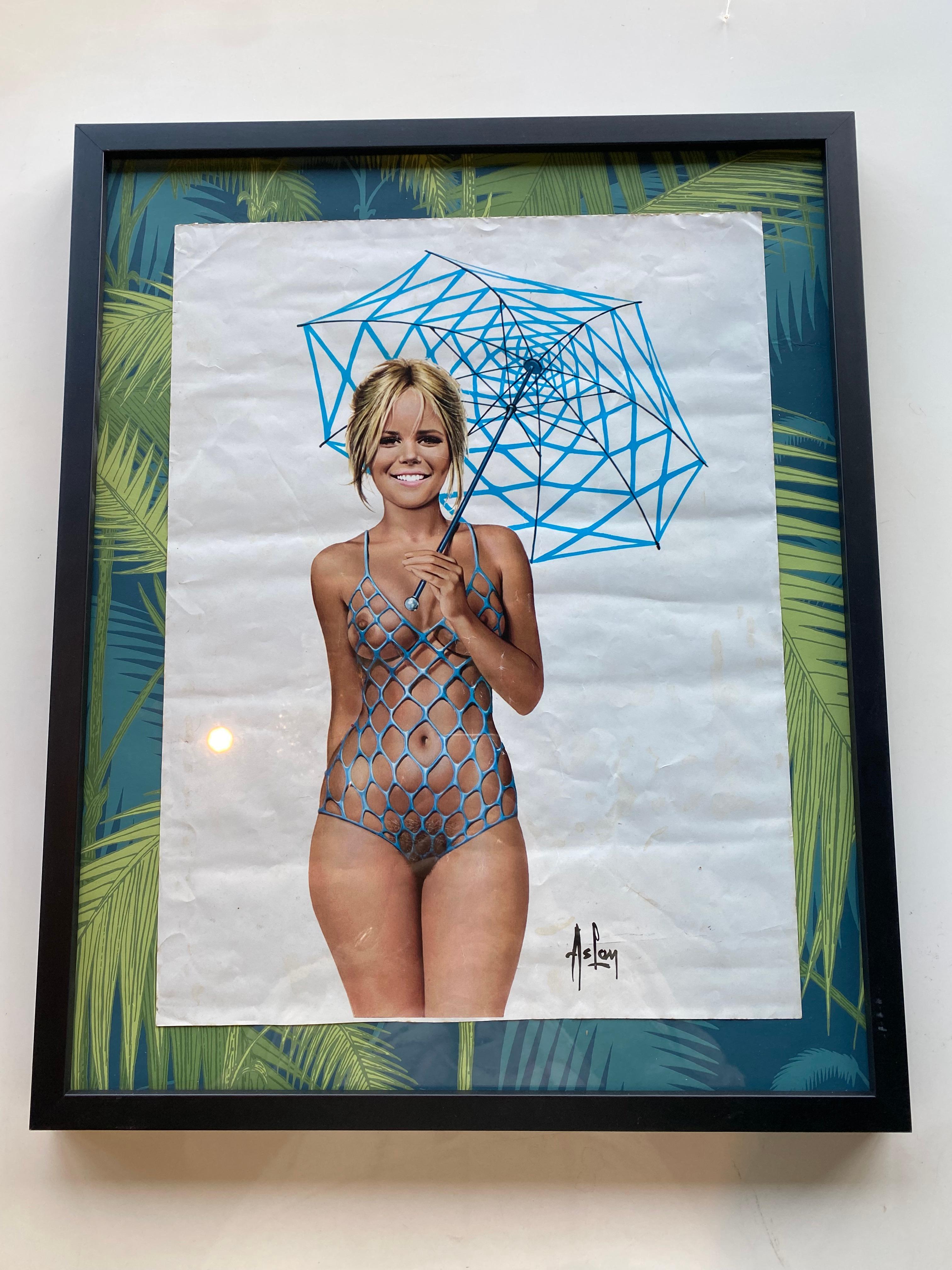 Framed print of a pin up girl circa 1970 by French artist Aslan.
The print of a 1970s pin up girl is framed behind glass and has been placed on a Cole and Son wallpaper. The offset print is quite worn and creased.
Aslan (born Alain Gourdon), (23