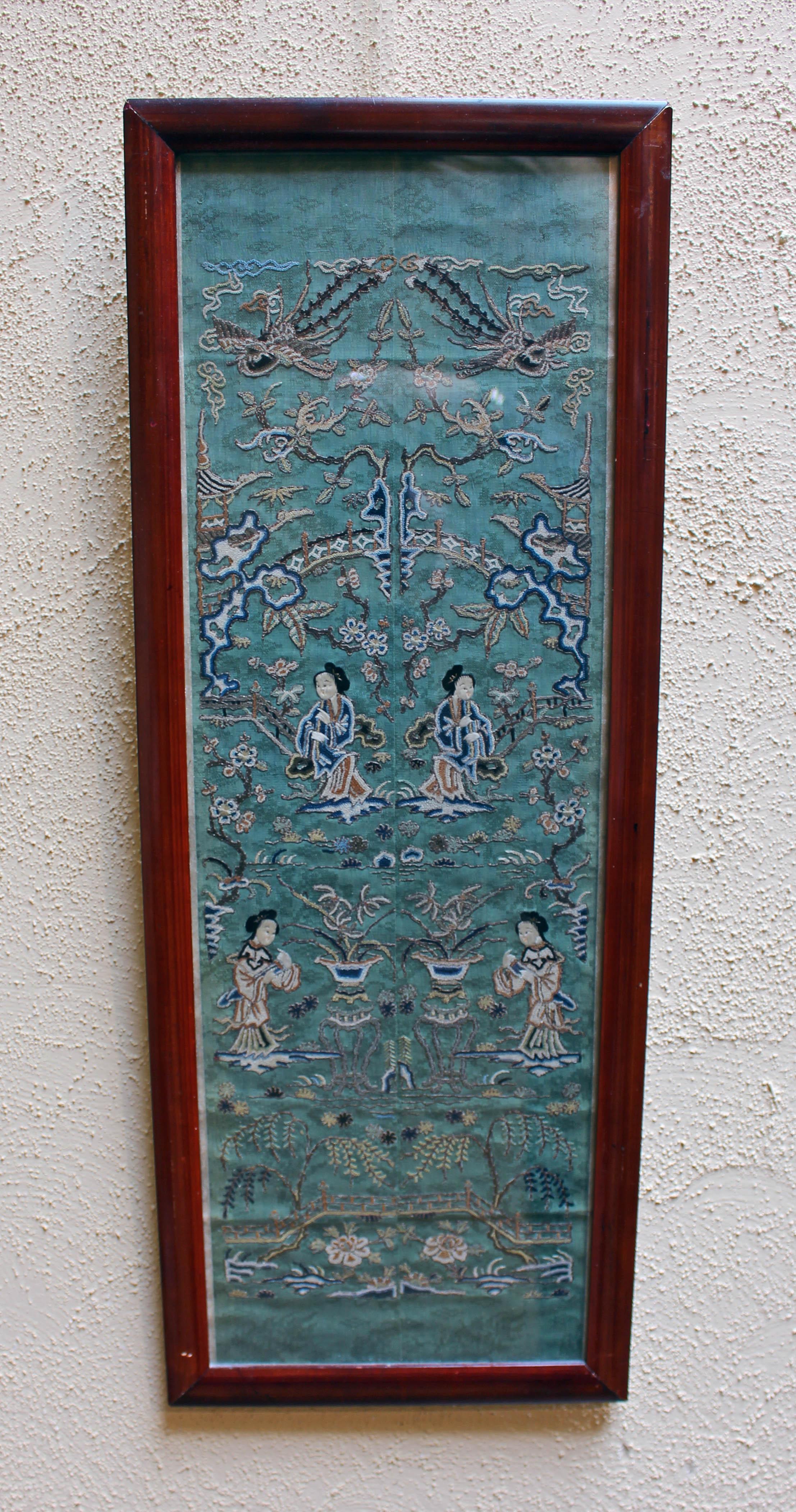 An exquisitely rendered sleeve panel, now framed, of silk embroidery on woven patterned green silk, displaying gold and silver threads, chain stitching and flat stitching. Phoenix birds soar over tea houses above garden and bridges. Late 19th