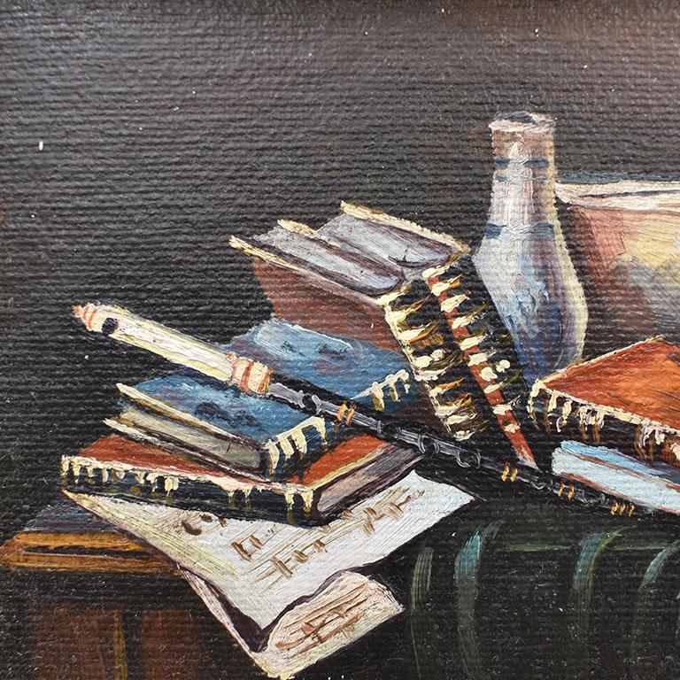 A traditional still-life painting of a variety of books. This pretty piece is framed in a gilt faux fern leaf frame with gold details. The painting is small and features a set of books with a vase upon a desk with green velvet. The piece is