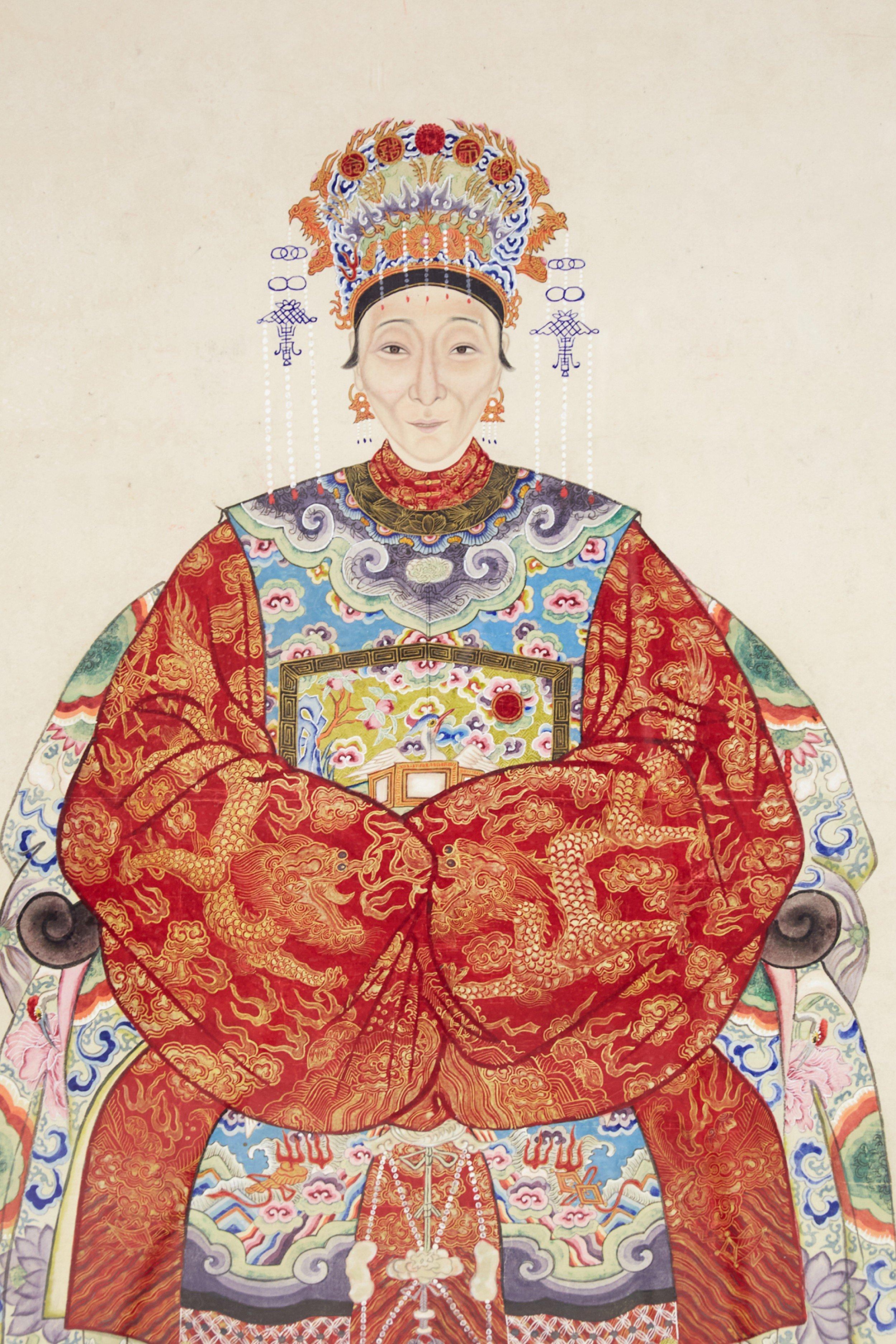 Vintage (20th Century) Chinese pen and ink ancestor portrait capturing the honoree seated and wearing an elaborate hat and red dress, on a beige background with a sage green floral patterned fabric mat, set in a rectangular walnut frame.
  