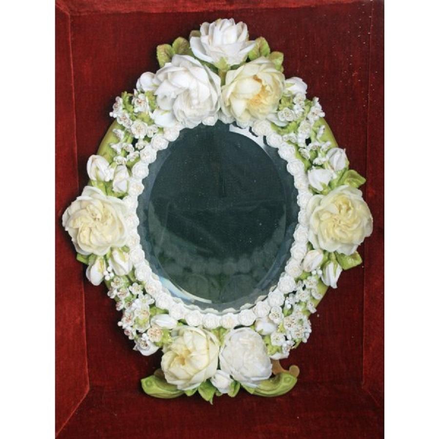 A very unusual Victorian oval dressing mirror.

The mirror is encased with a frame made from wax flowers and leaves the detail of which is amazing with each individual petal made from shaped and coloured wax.

The mirror is mounted on a gilt