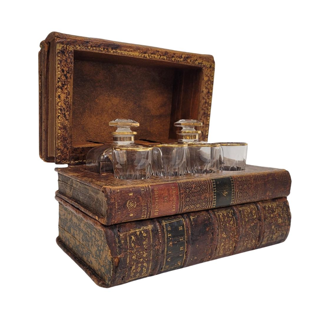 Amazing  Tántalo or book-shaped leather box concealing a beautiful wheel-engraved crystal set, outlined in gold, consisting of two bottles with their stoppers and four finely engraved glasses, making it an exquisite French bottle holder from the