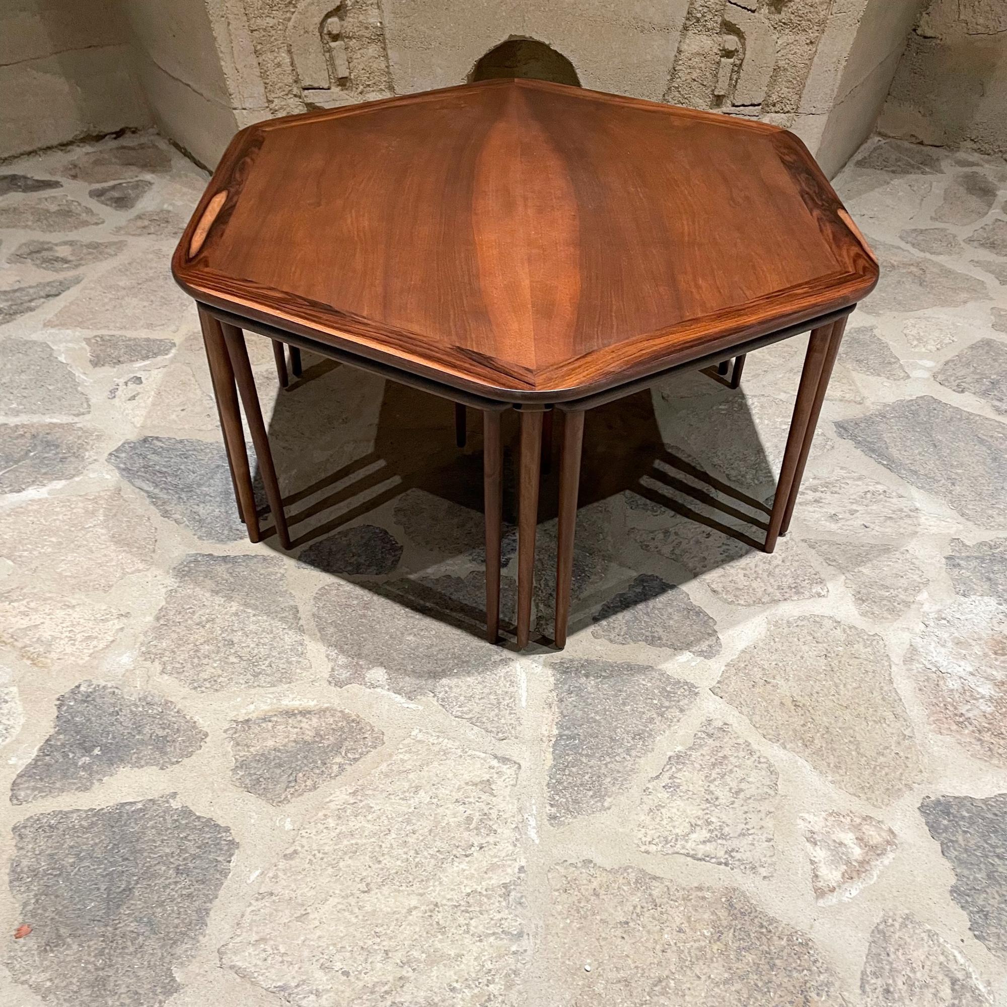 Set of 6 rosewood nesting tables tucked underneath hexagonal coffee table. 
Made Denmark 1950s
Set includes 7 pieces.
 17.38 tall x 34.13 depth x .38 at widest point.
Triangular side tables are 16.38 tall x 17 x 17
Table retains original stamp.