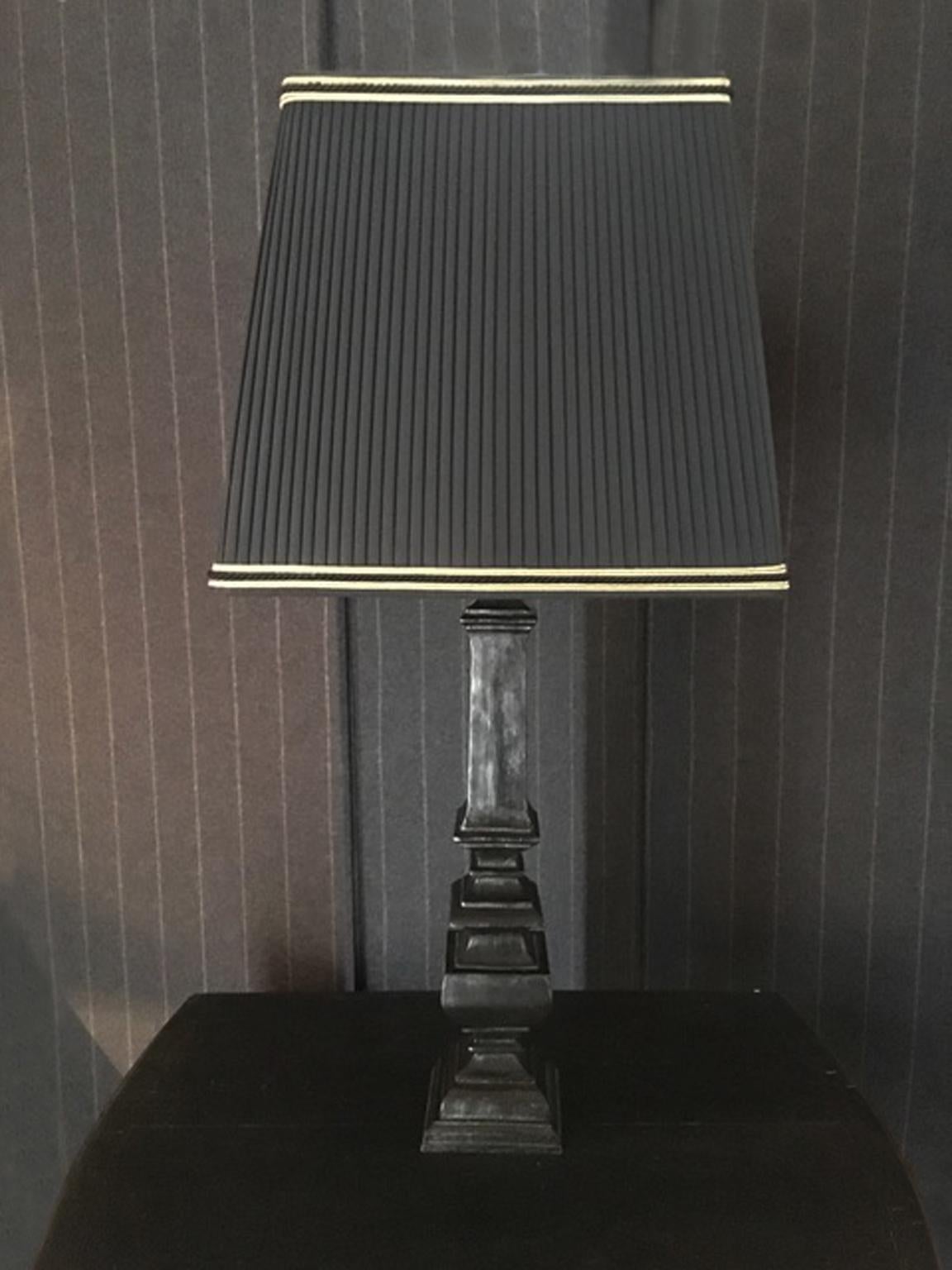 This elegant table lamp, is made in black laquered wood, the shape is as an handcrafted production and shows the irregular surface to imitate the signs of the past.
The pleated lamps shade, is a fine made in Italy production, the black fabric is