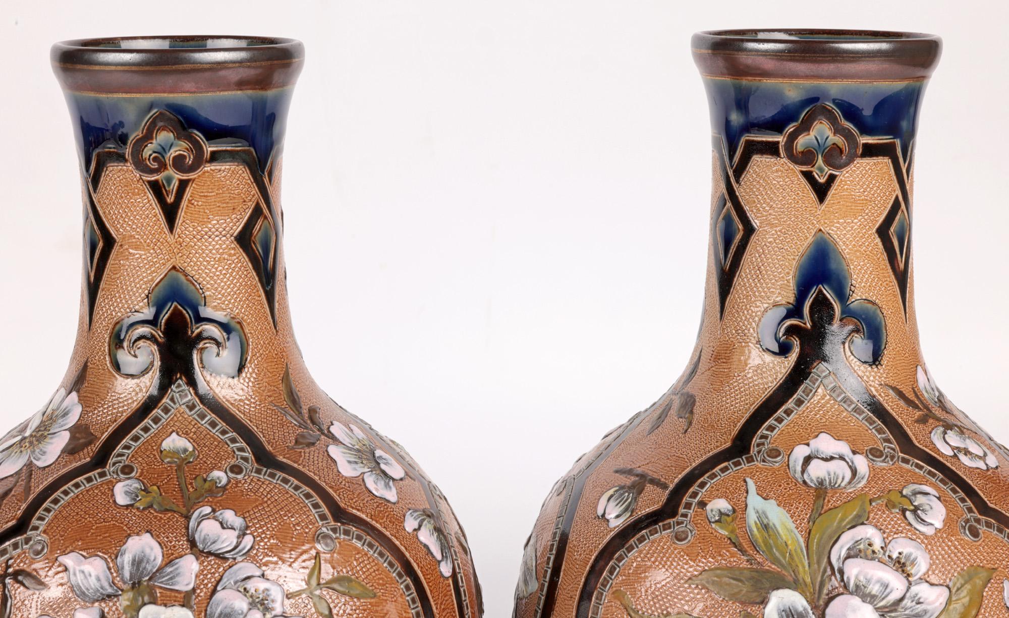 A large and impressive pair Doulton Lambeth Slaters pâte-sur-pâte style floral painted vases by renowned designer and decorator Frances E Lee and dating from around 1885. The large stoneware bottle shaped vases stand raised on a narrow round foot
