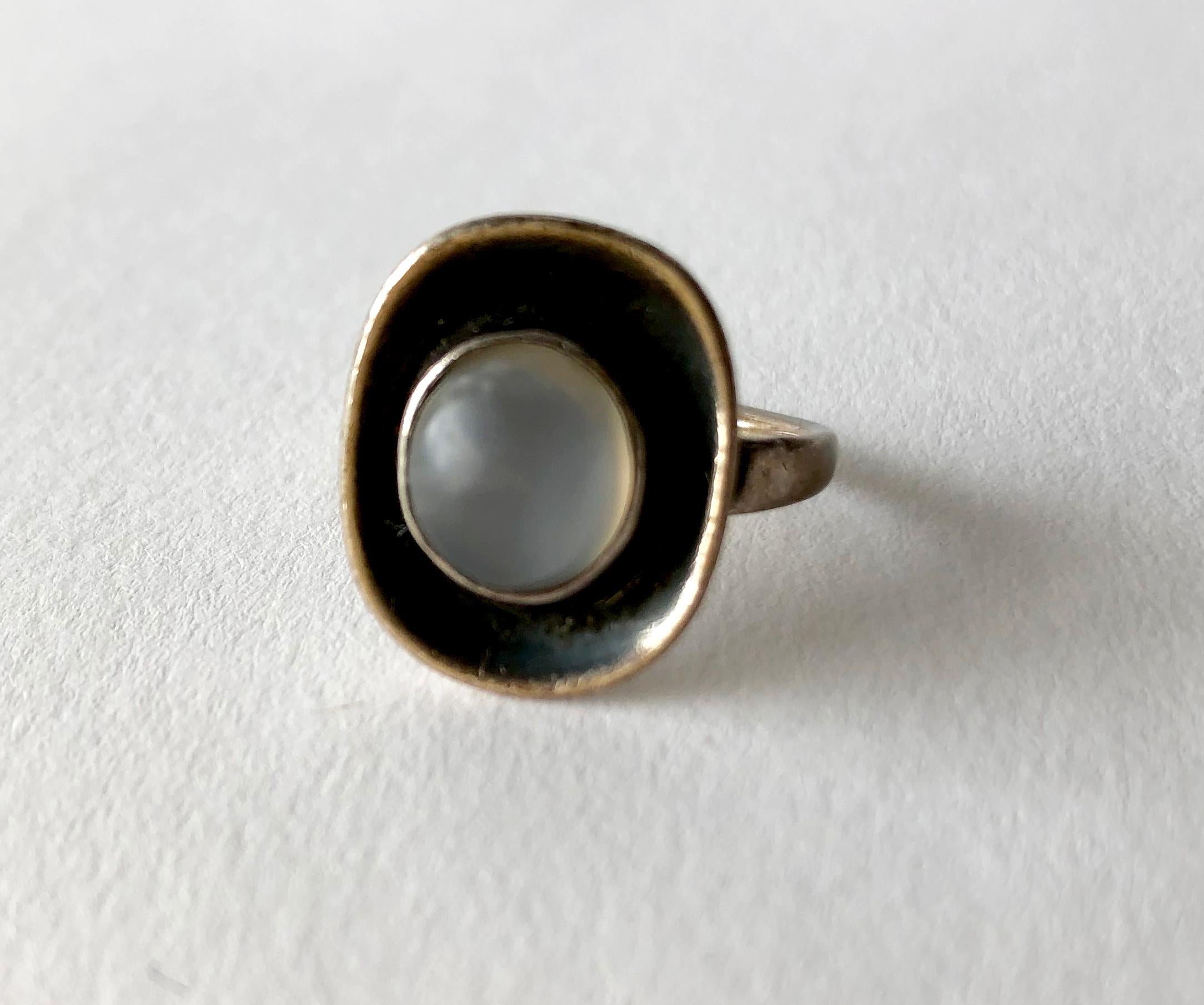 American modernist sterling silver and moonstone ring created by Frances Holmes Boothby of Weston, Vermont.  The moonstone changes color in different light settings. Rings face measures approximately  3/4