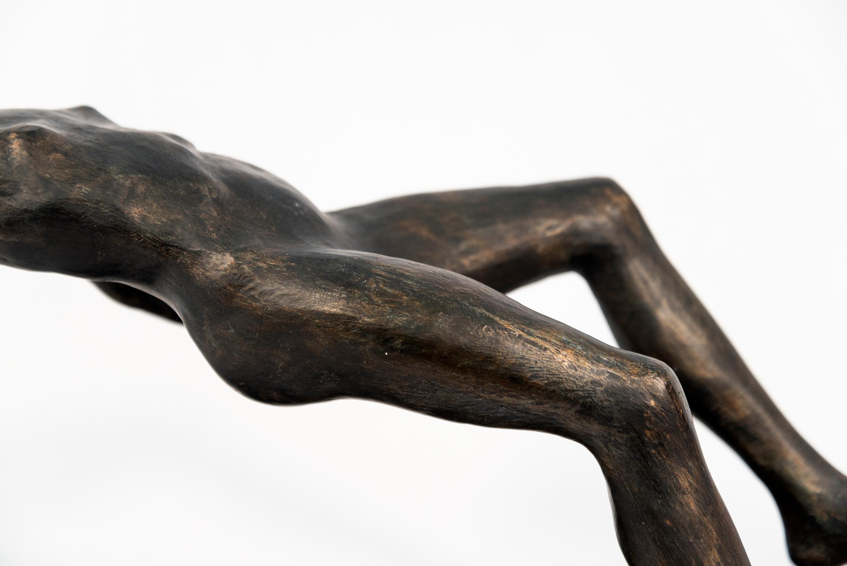 Frances Semple’s beautiful and elegant sculptures often appear in motion. Defying gravity, a horizontal figure appears to float on its back above its shadow. This table top piece is made of resin and has a black wood base. Is the title a reference