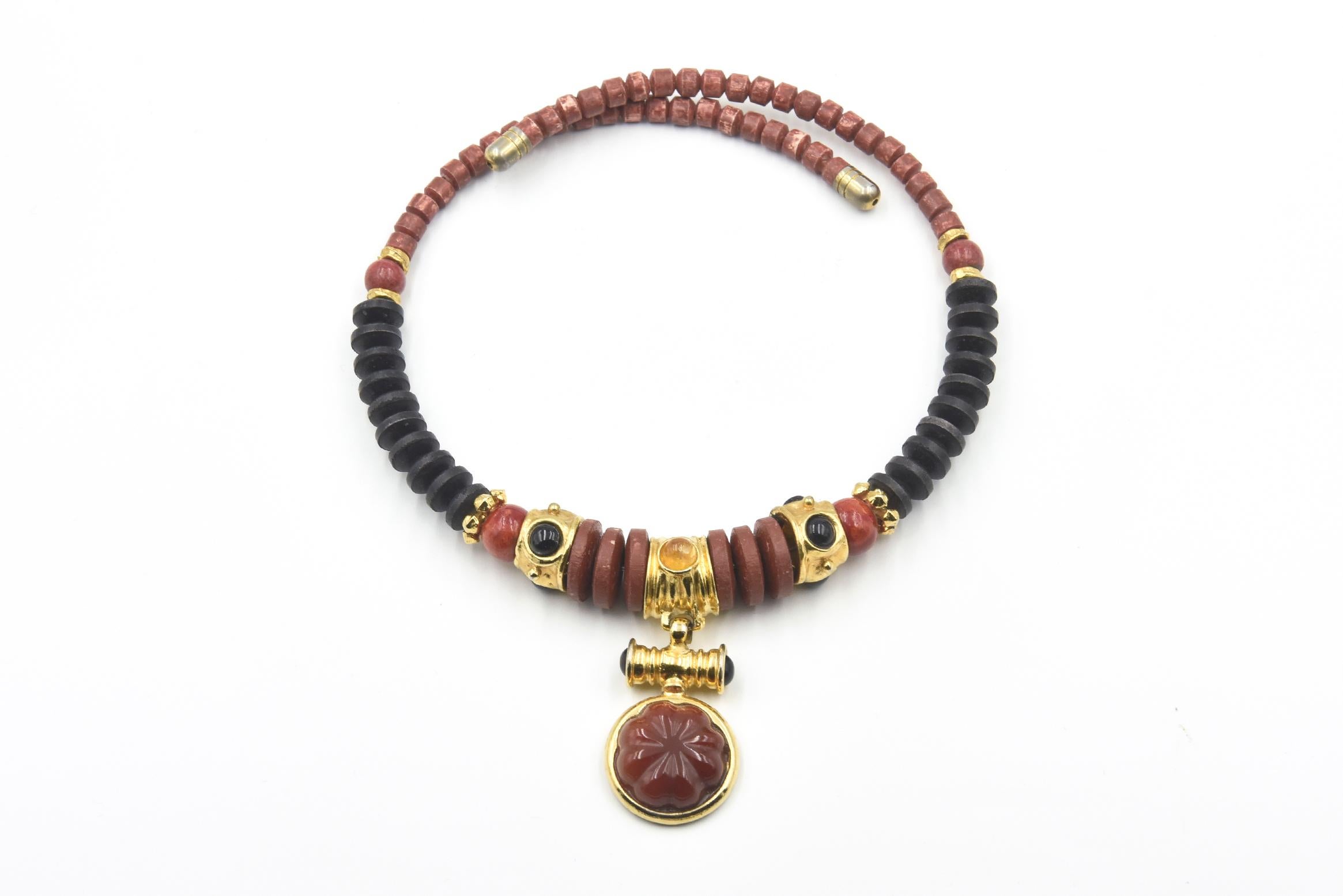 Handcrafted goldtone metal and wood bead necklace with a floral glass pendant and goldtone metal hoop earrings set with black stones. Post-back earrings: 1