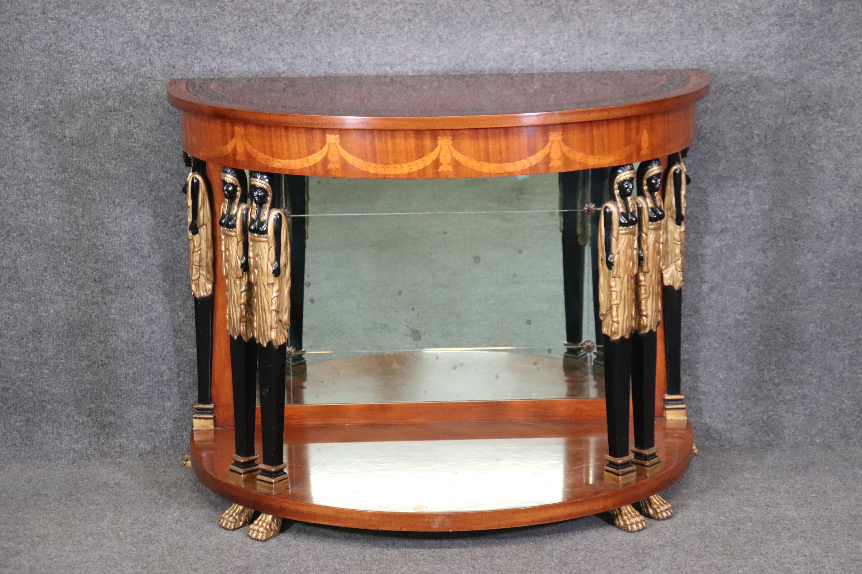 This is a fantastic Egyptian revival style inlaid satinwood and walnut demilune console table with painted and gilded figures and a faceted multi-paned mirrored back. The top is inlaid in a stretched Greek key motif and the table is in good original