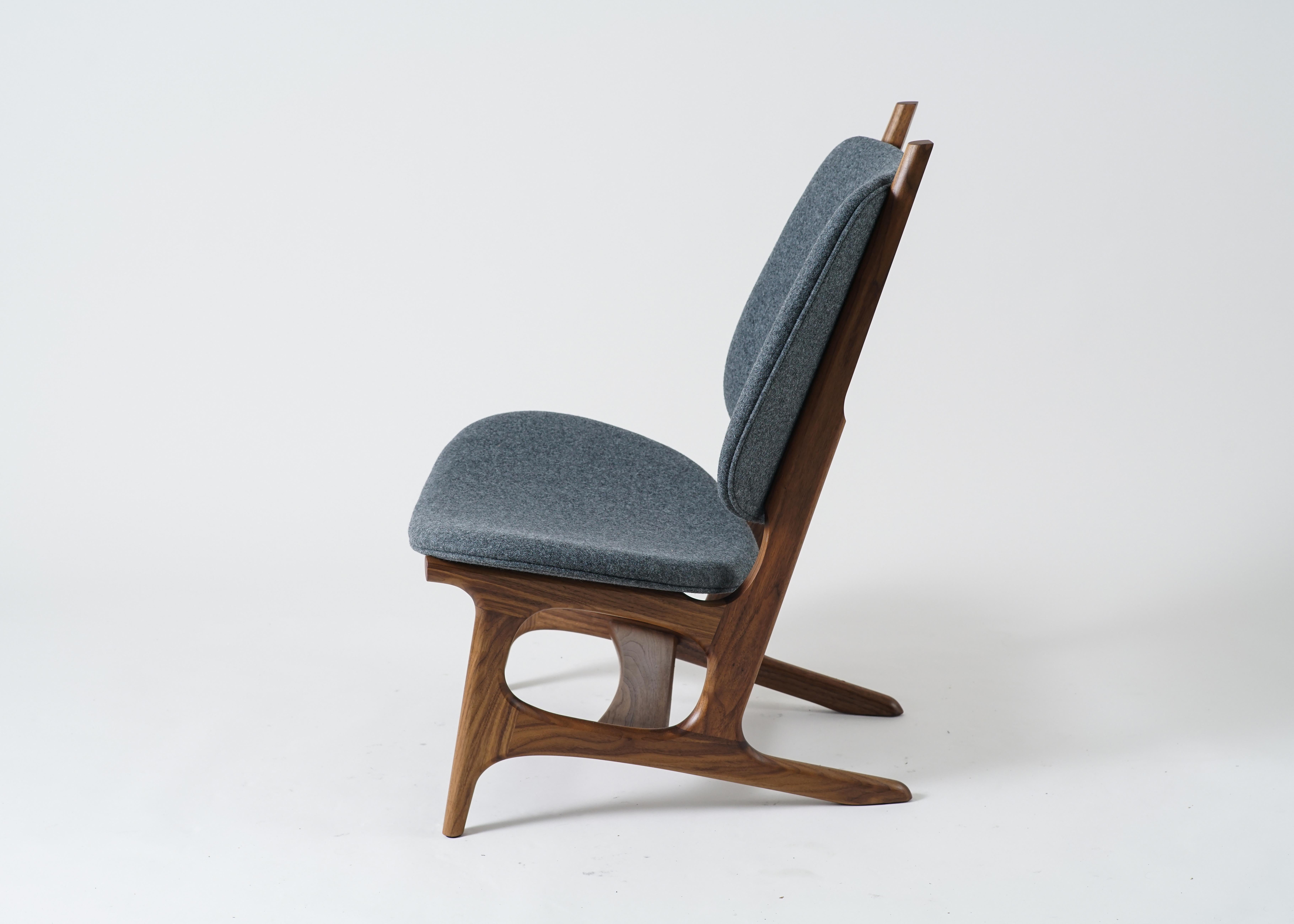 Der Francis Sessel von Phloem Studio ist ein moderner, übergroßer Sessel mit einem Gestell aus massivem Walnussholz und einer gepolsterten Sitzfläche und Rückenlehne mit Wollbezug. Francis ist ein geräumiger Sessel, in dem man Americanos oder Wein
