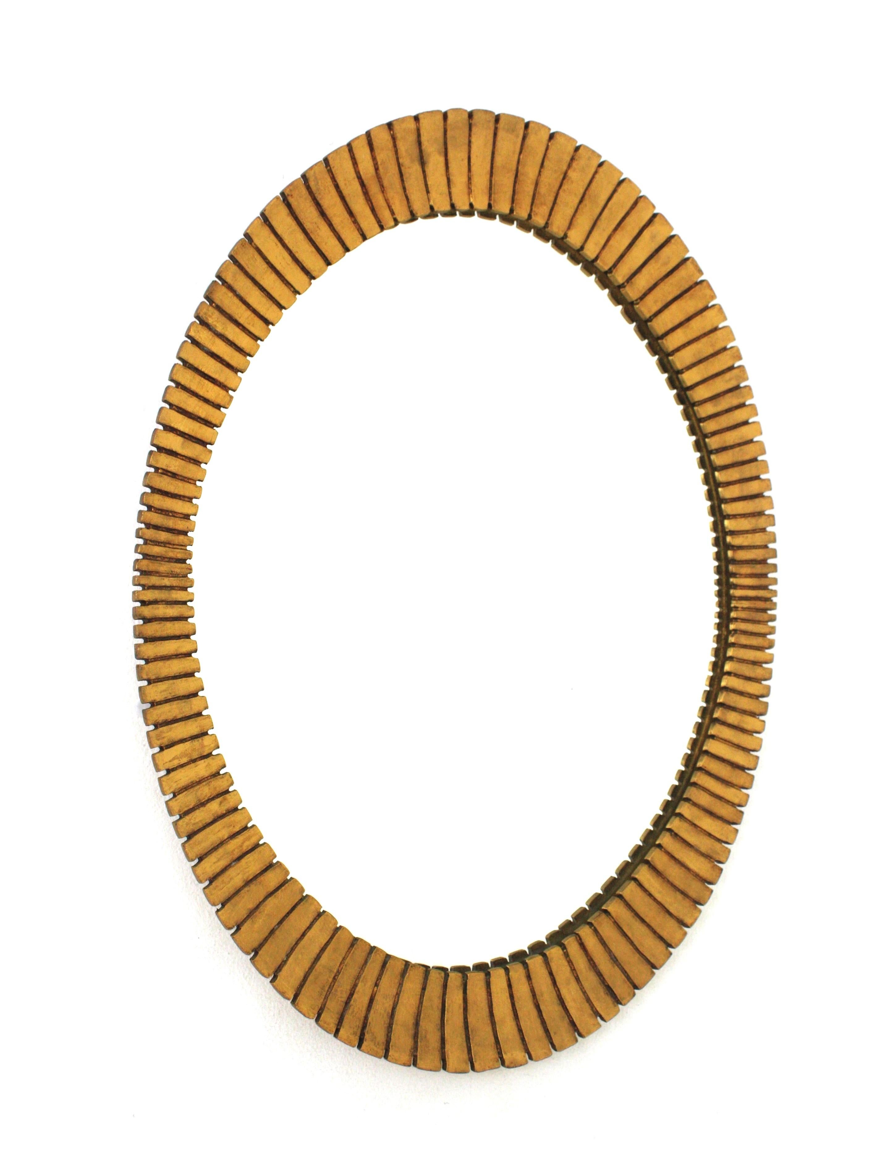 Magnifique miroir ovale en bois doré festonné avec finition à la feuille d'or dans le style Hollywood Regency. Espagne, années 1950
Fabriqué par l'ébéniste espagnol Francisco Hurtado. 
Cadre de forme ovoïde avec des rayures finement sculptées et un