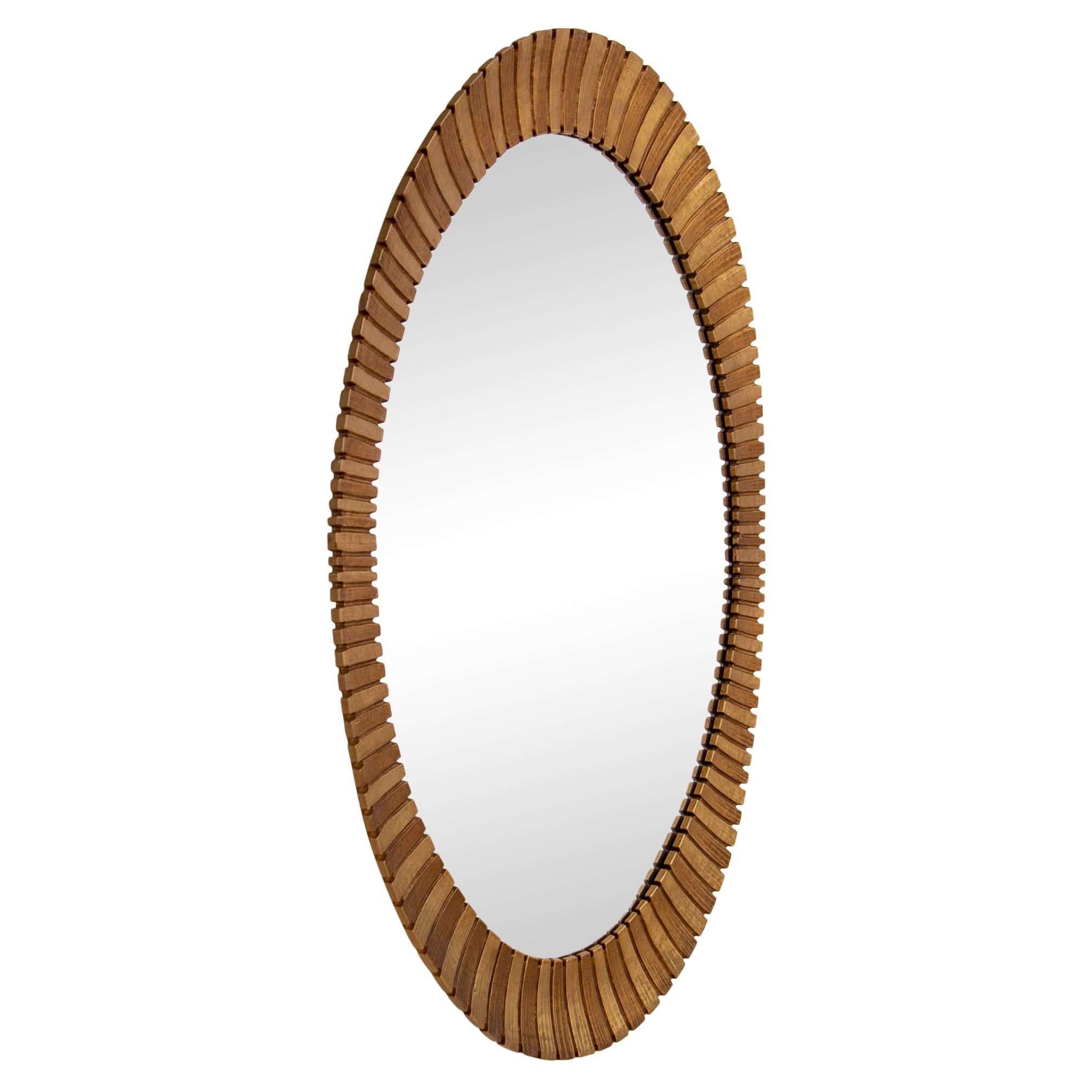 Mid-century large oval mirror in the style of Francisco Hurtado, circa 1970s. The durable cast resin frame features graduated concave scallops in alternating bronze and gold tones. It may be hung vertically or horizontally. Minimal age wear to the