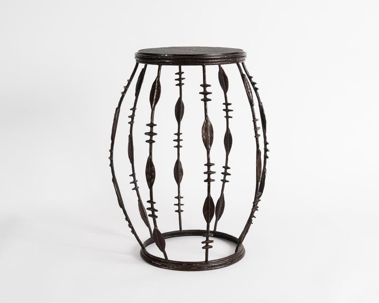 This barrel-shaped occasional table by French artist Franck Evennou was originally conceived as a pedestal for rare African sculptures and masks. The piece is supported by bands of black patinated, sand cast bronze and covered with a dark slate