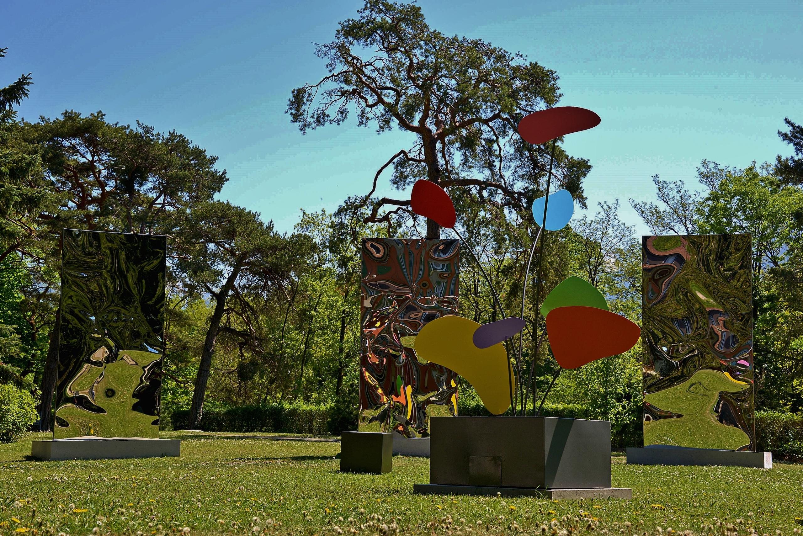 Psyche is a unique installation of three mirror-polished stainless steel sculptures on a concrete base and three painted stainless steel stabiles and bases by contemporary artist Franck K, dimensions are 300 × 510 × 280 cm (118.1 × 200.8 × 110.2