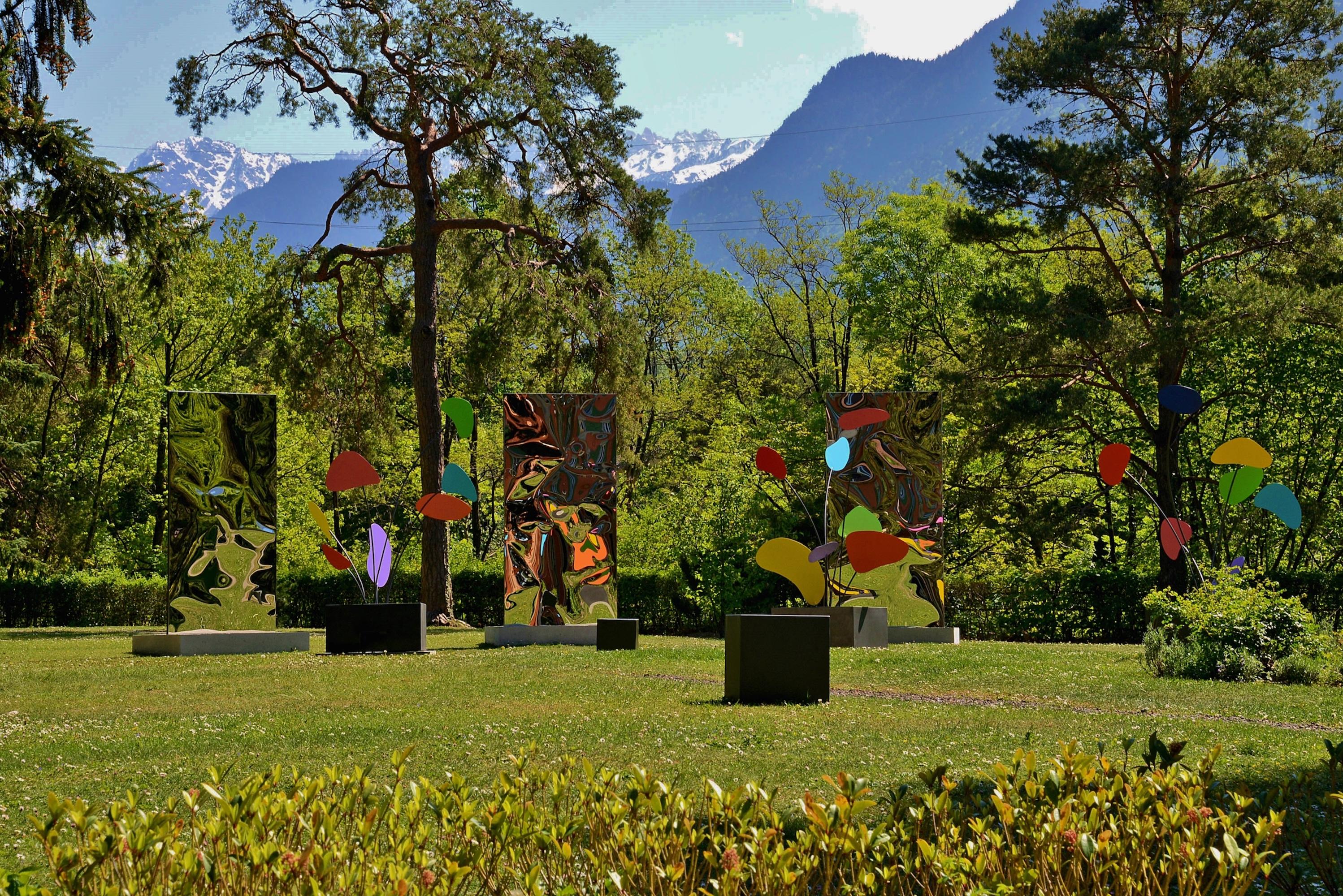 Psyche is a unique installation of three mirror-polished stainless steel sculptures on a concrete base and three painted stainless steel stabiles and bases by contemporary artist Franck K, dimensions are 300 × 510 × 280 cm (118.1 × 200.8 × 110.2