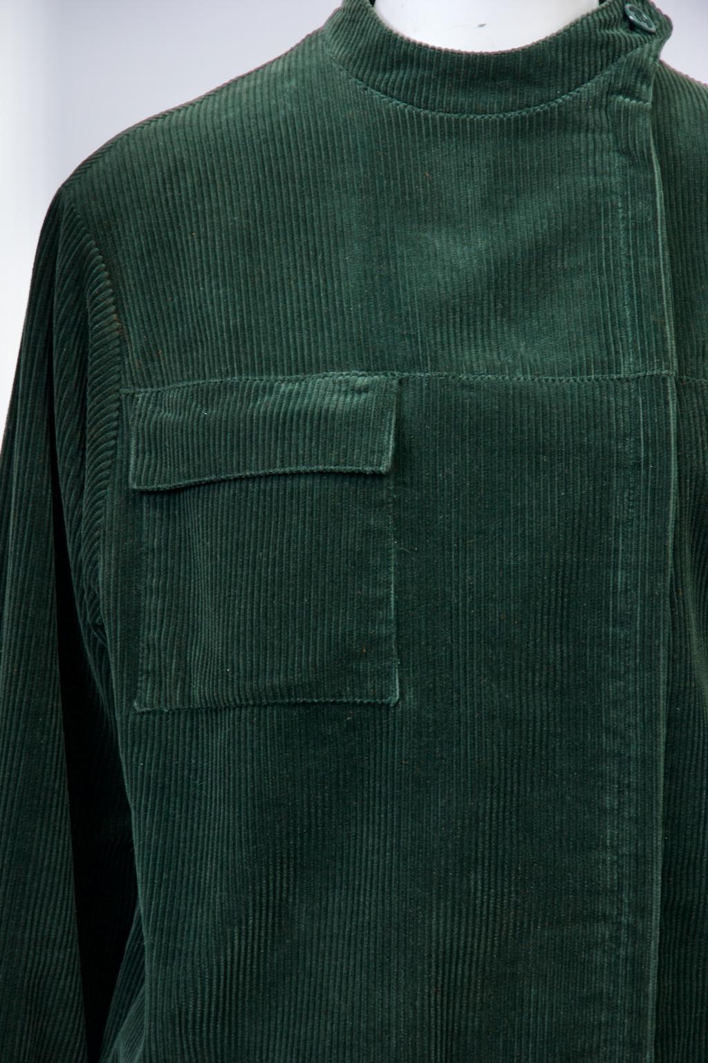 Die jagdgrüne Cordjacke von Franck Olivier hat einen dezentralen Reißverschluss, einen Mandarinenkragen und koordinierte Strickbündchen an Hüfte und Handgelenken. Eine aufgesetzte Tasche mit Patte oben rechts an der Jacke sorgt für zusätzliche