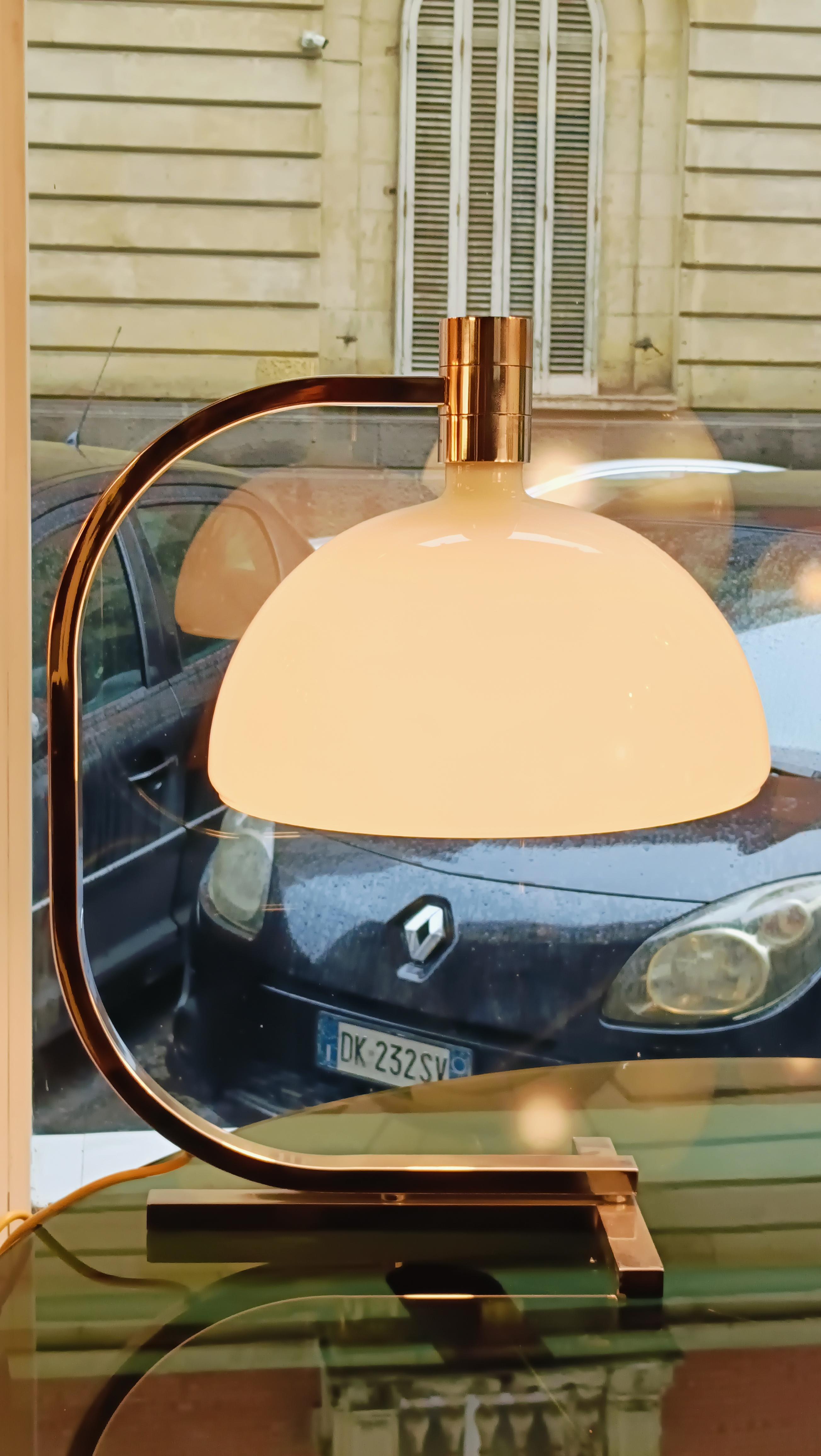 AS1C designed by Fanco Albini and Franca Helg for Sirrah is a table lamp with a structure made entirely of chrome-plated metal. The cup-shaped diffuser is made of white opaline glass.