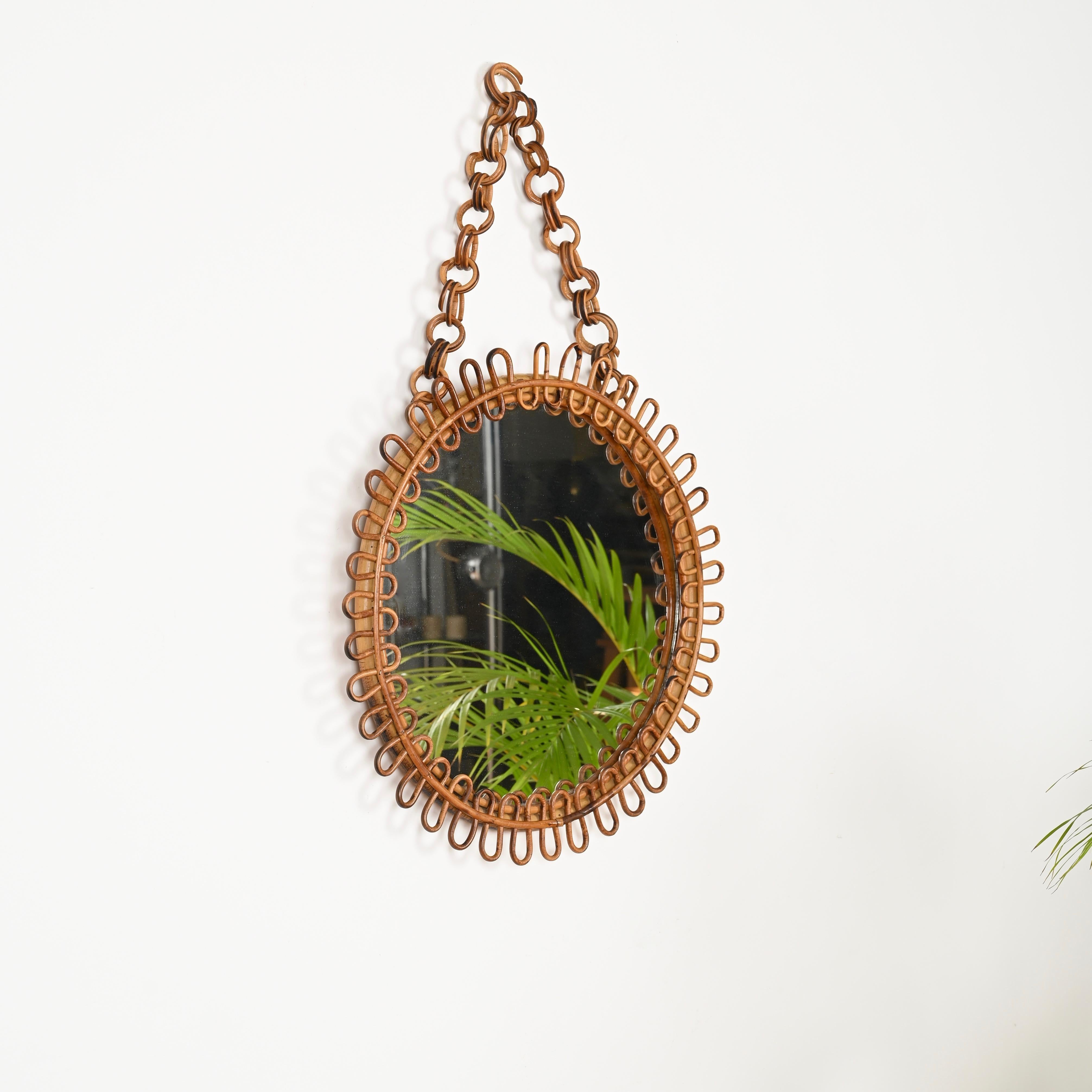 Stunning Mid-Century round mirror with chain fully made in cvurved rattan and bamboo. This charming French Riviera style mirror was produced in Italy during the 1960s.

In amazing condition and with a wonderful honey color. This organic mirror was